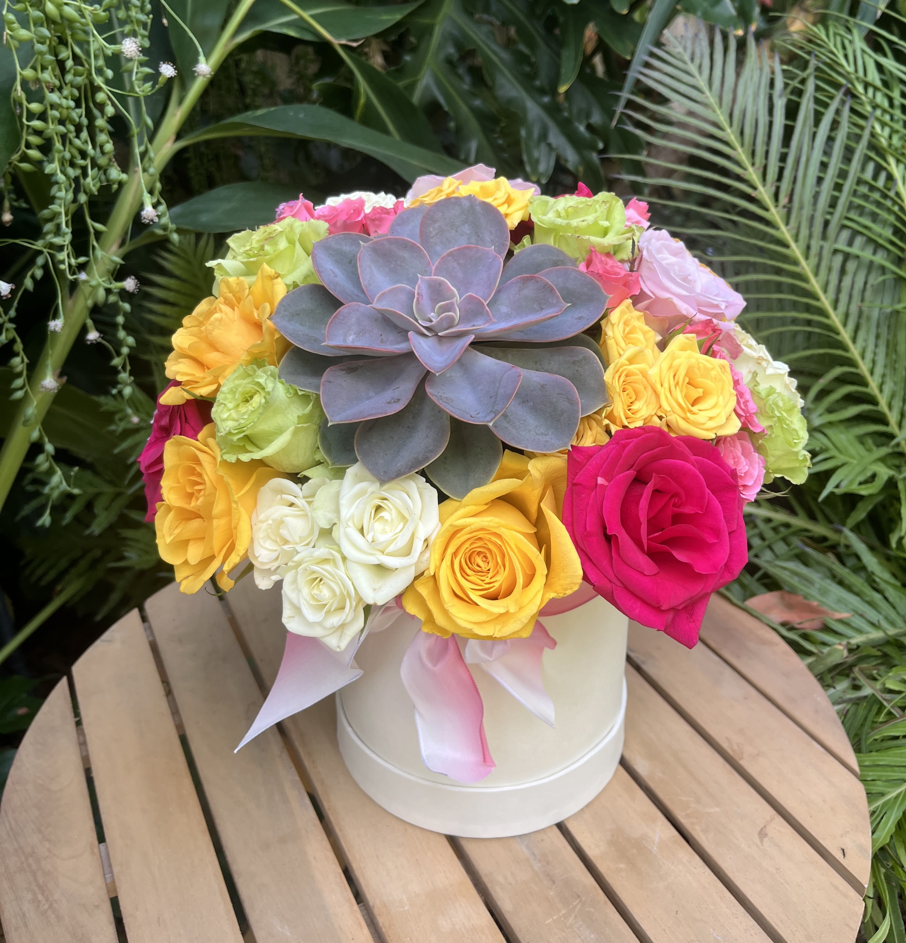 Colorful rose arrangement with a large succulent in a white hatbox
