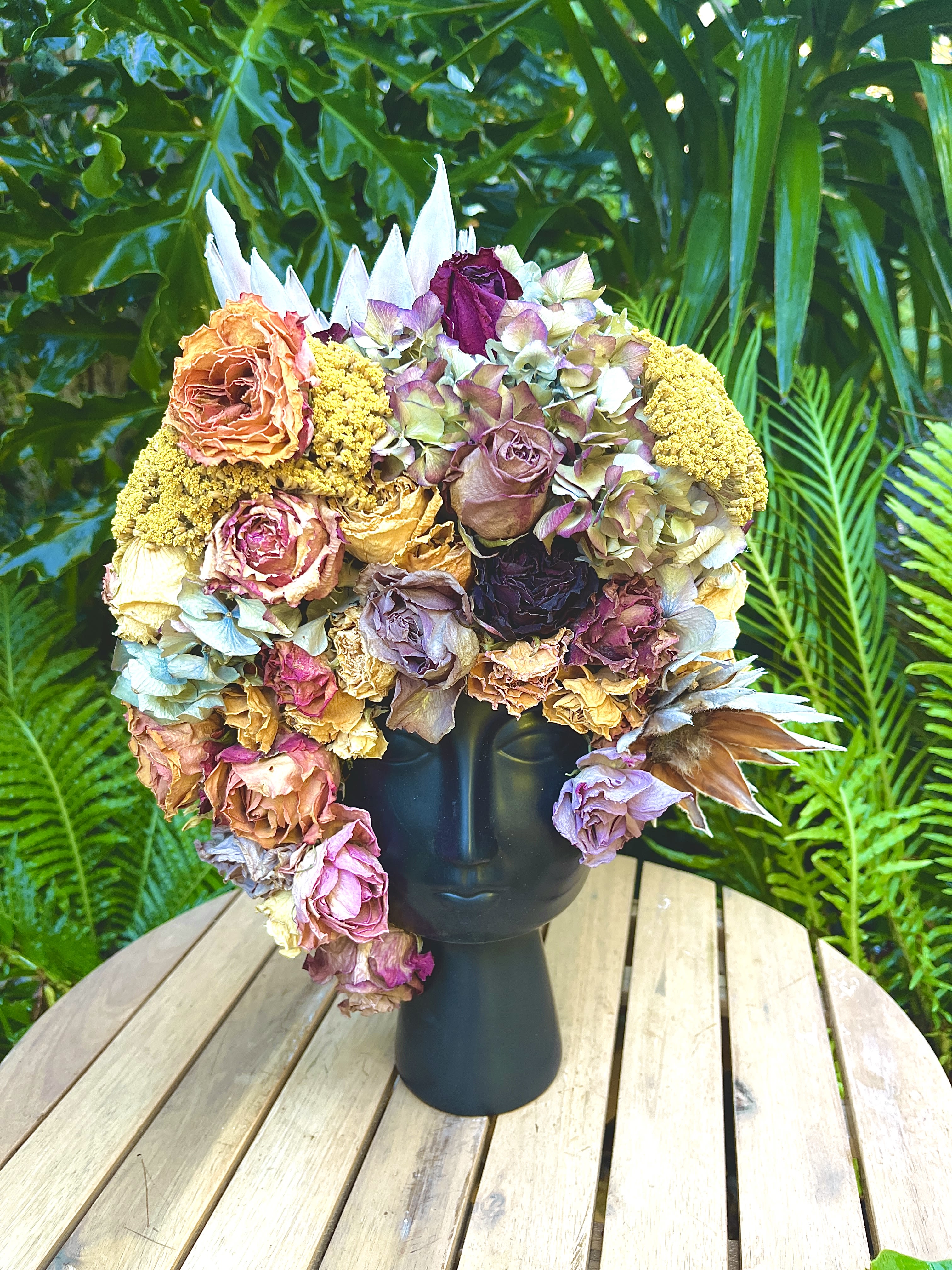 Large bouquet of dried roses and hydrangeas in a black vase