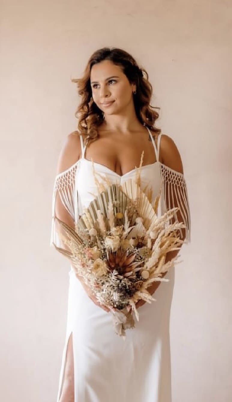Woman in a white dress holding a dried flower bouquet