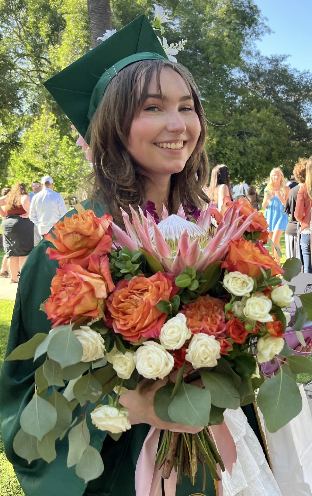 Graduate holding a bouquet of orange and white flowers
