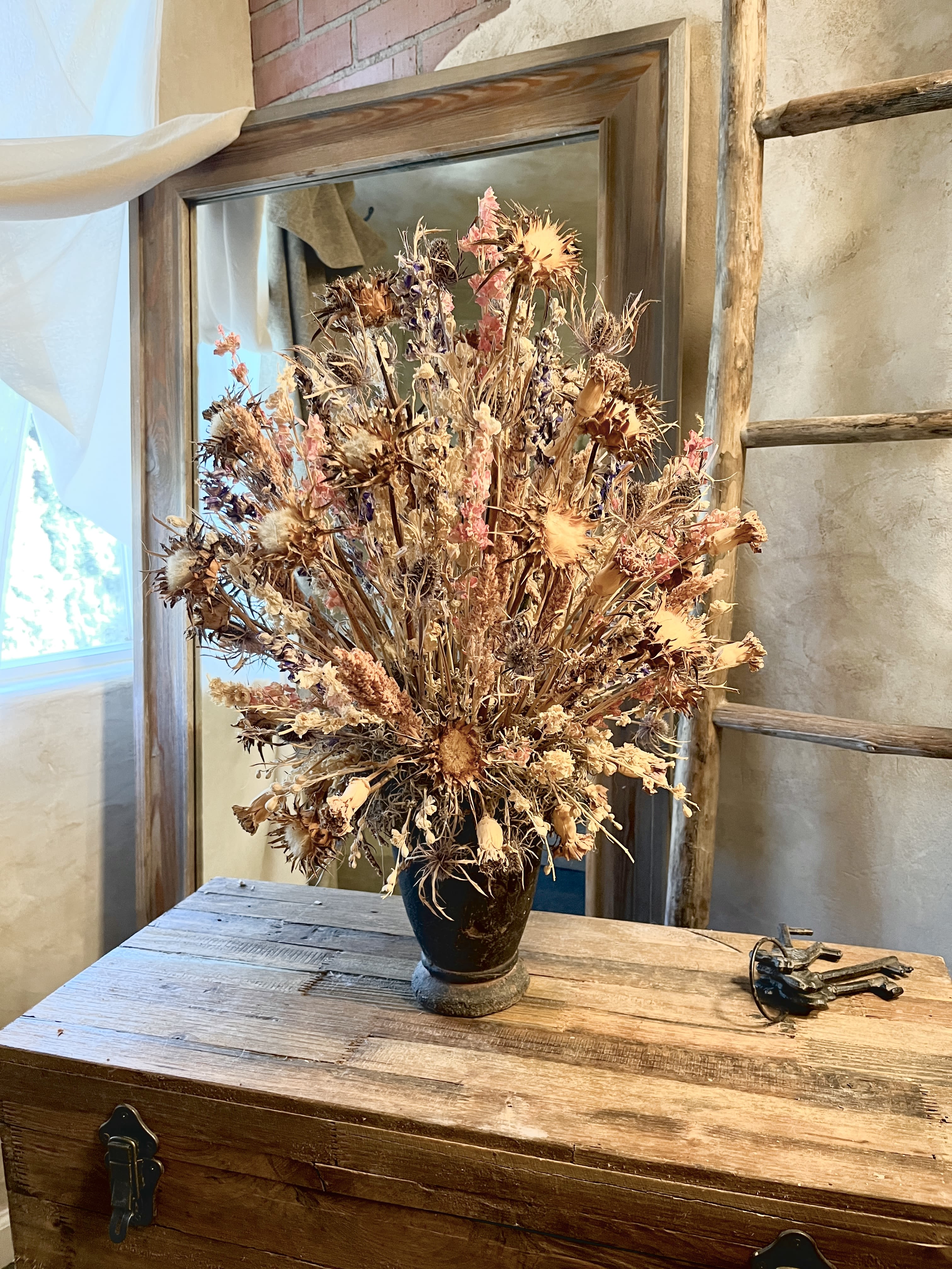 Dried wildflower arrangement in a dark vase on a wooden table