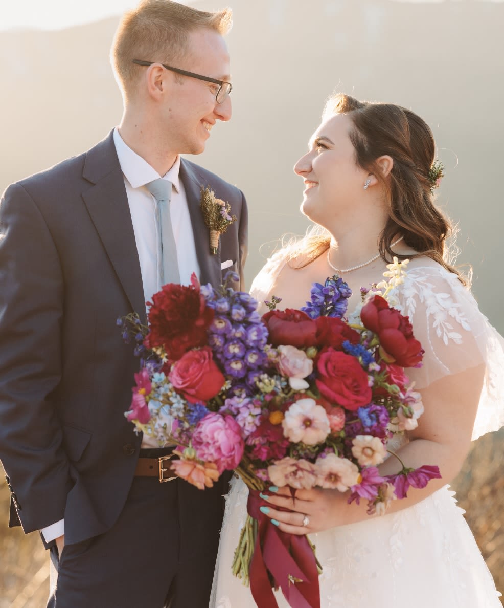 Bride and groom holding a colorful wedding bouquet and boutonniere