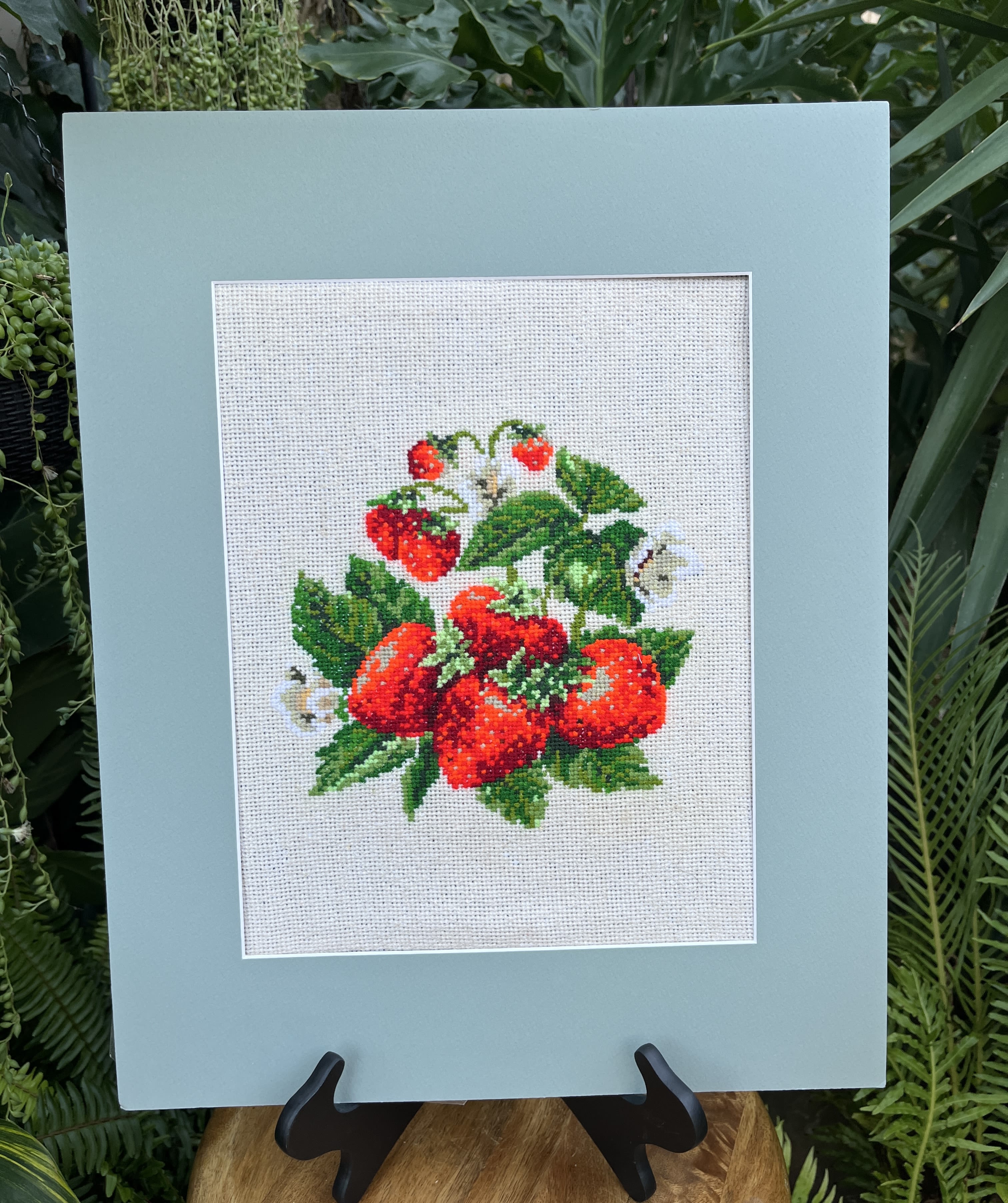 Framed cross-stitch of red strawberries and green leaves