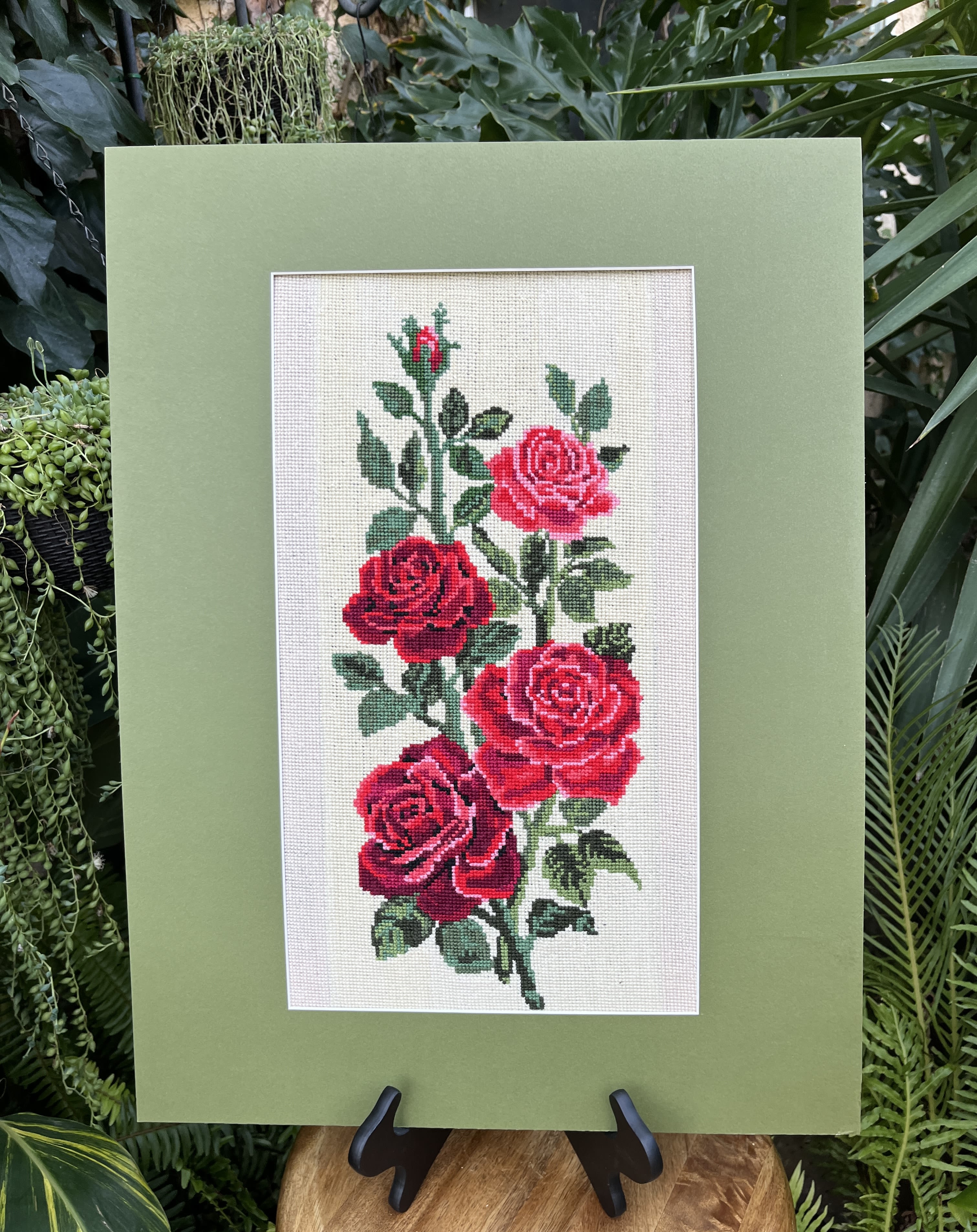 Framed embroidery of red roses on a green mat board