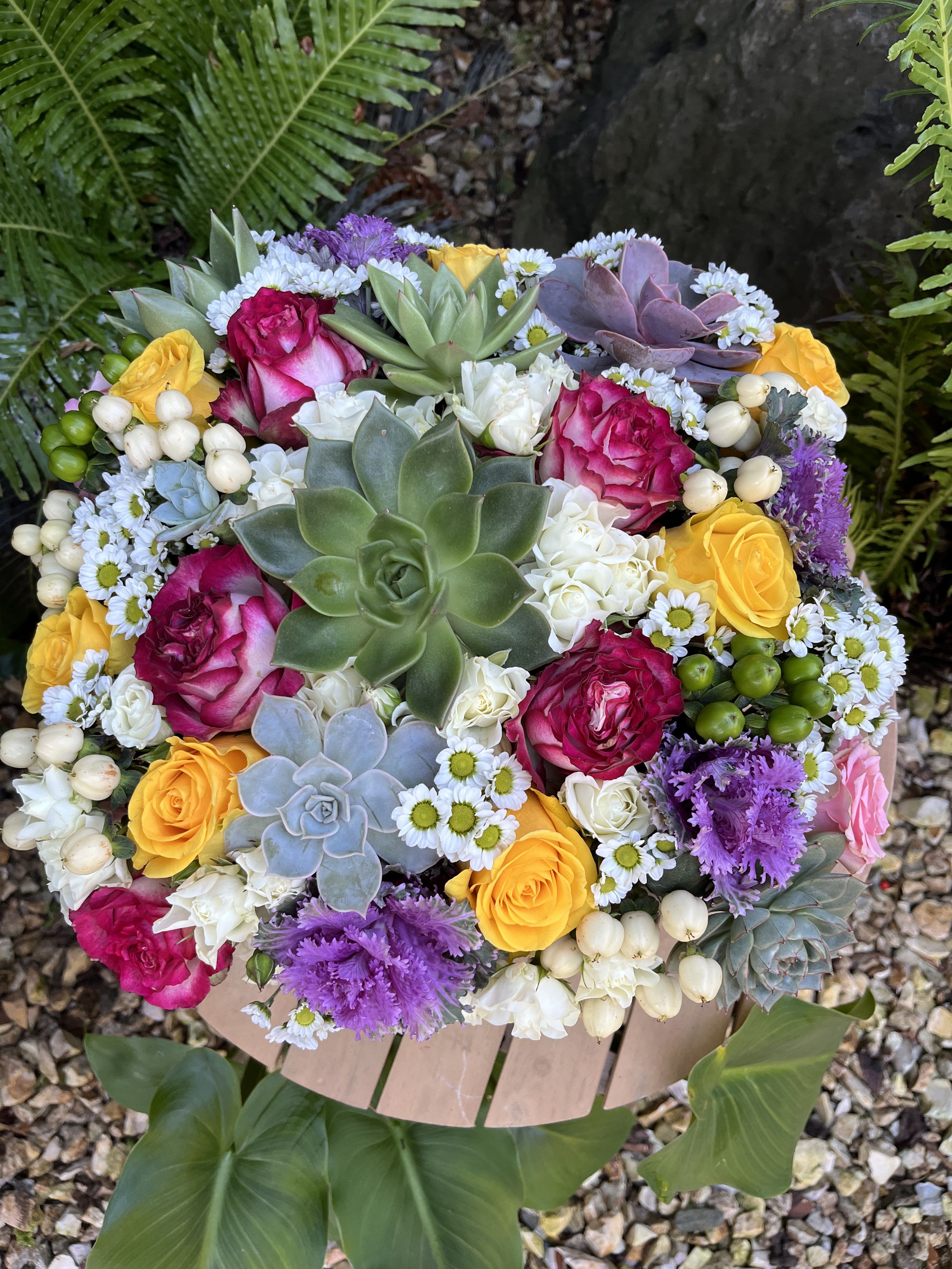 Round bouquet with pink and yellow roses, succulents, and small white daisies