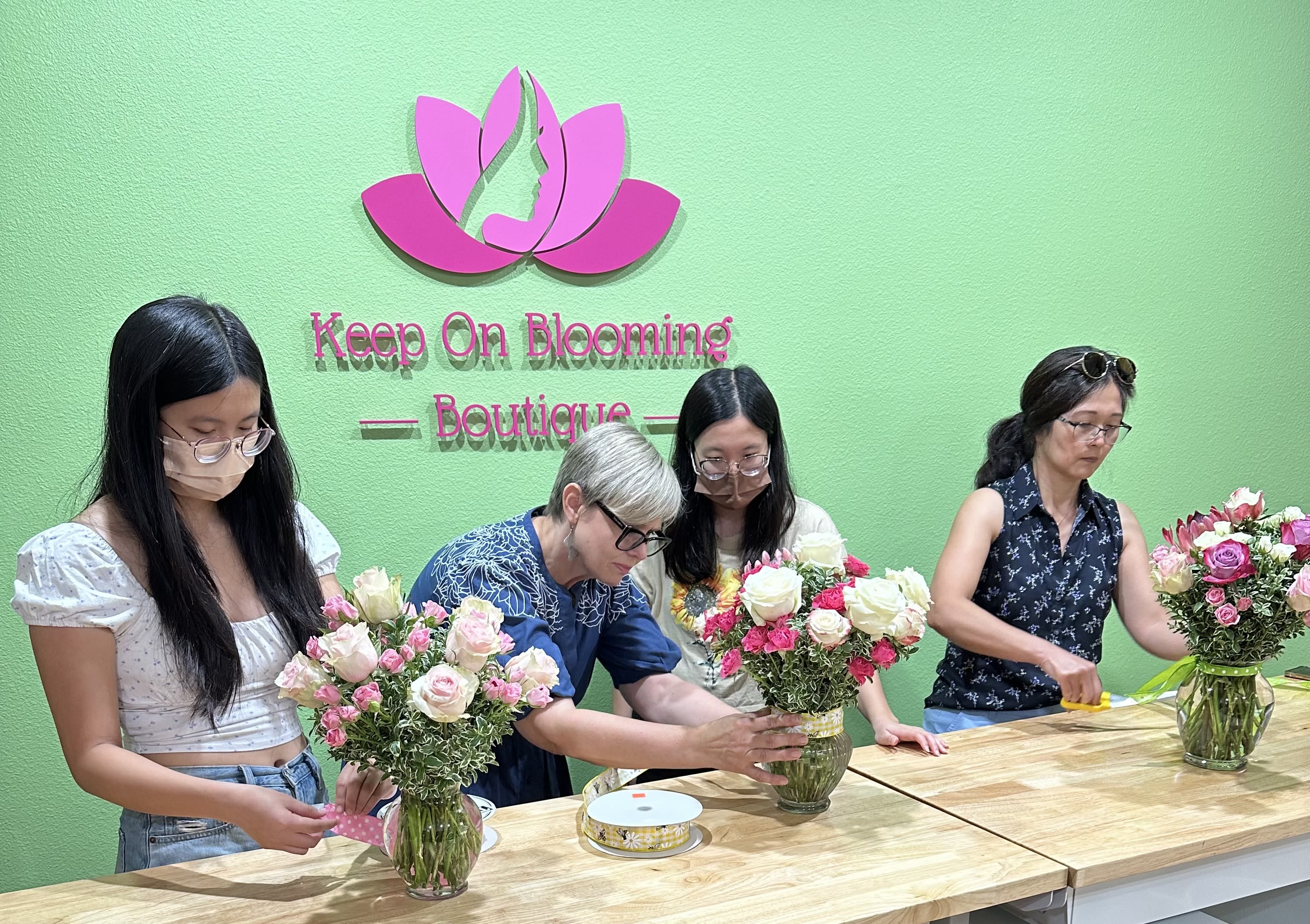 People arranging pink and white rose bouquets in glass vases