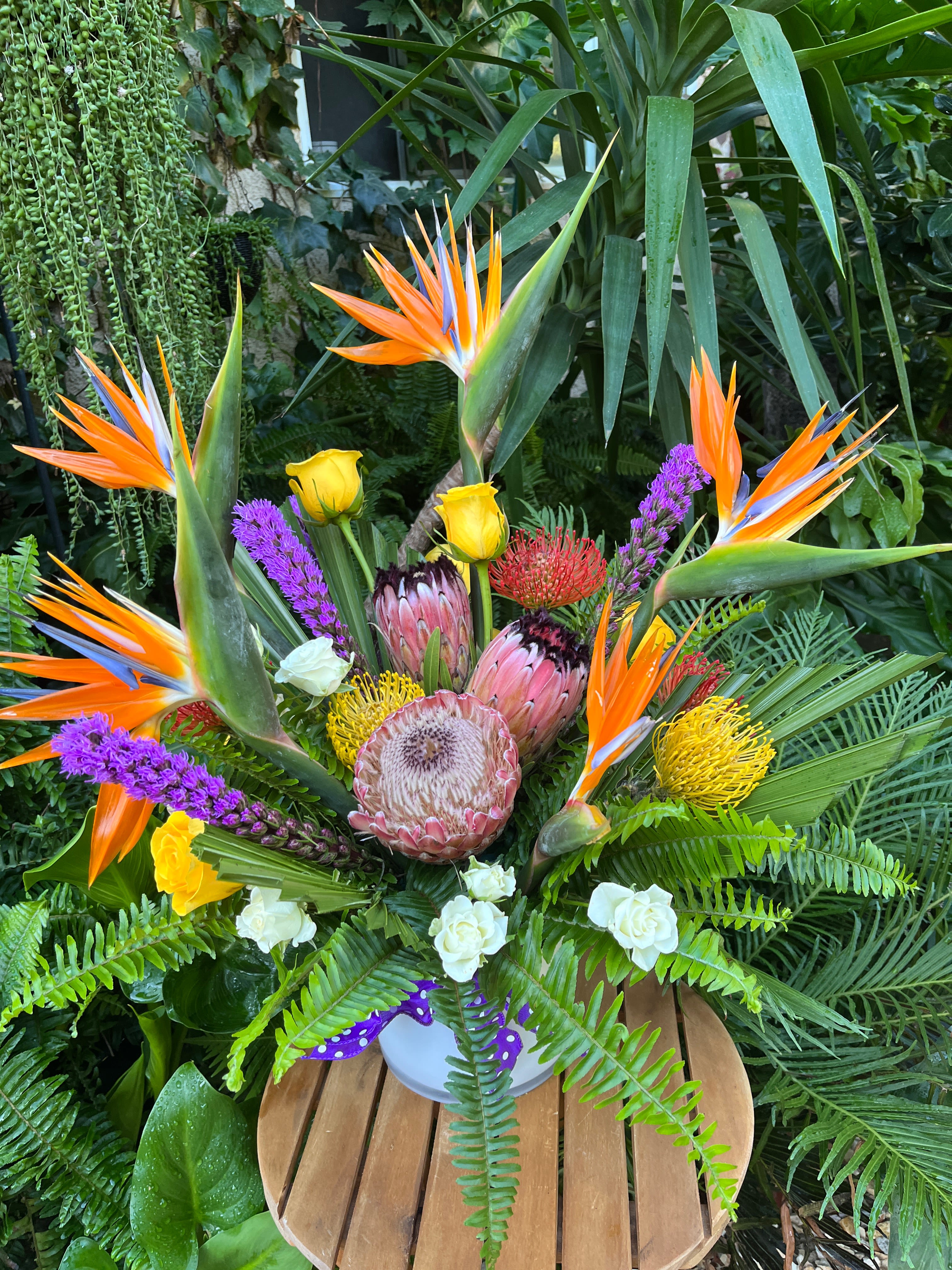 Tropical bouquet with bird of paradise, protea, and roses in a vase