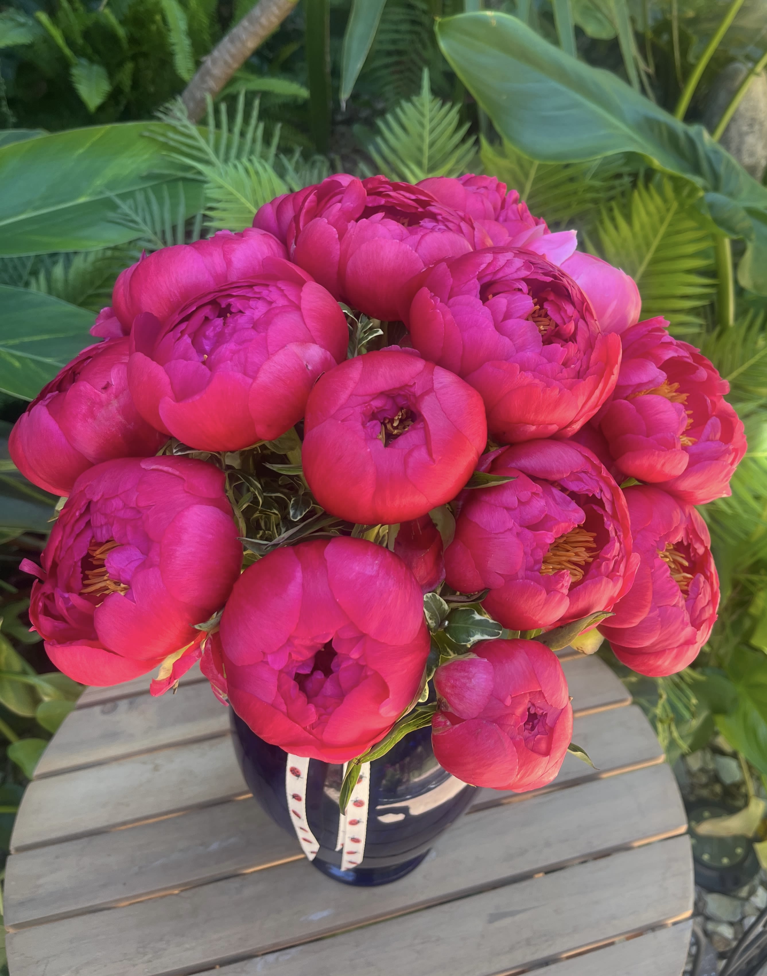 Bouquet of bright pink peonies in a dark vase