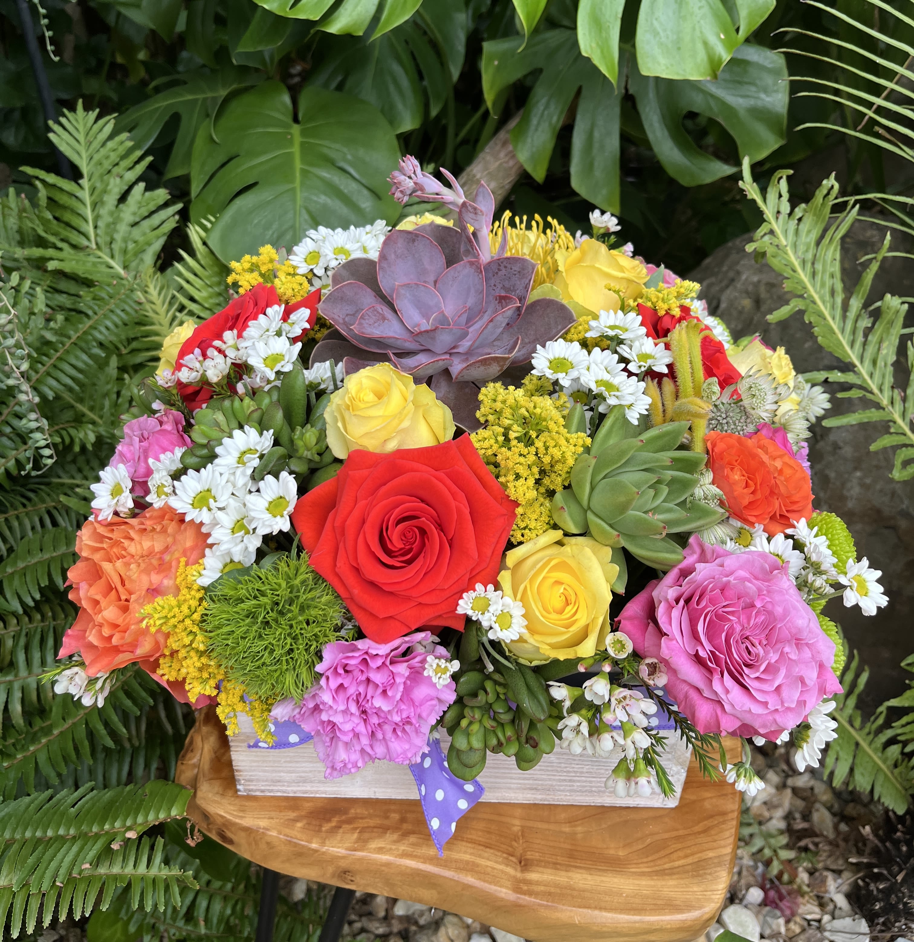 Colorful bouquet with roses, daisies, and succulents in a wooden box