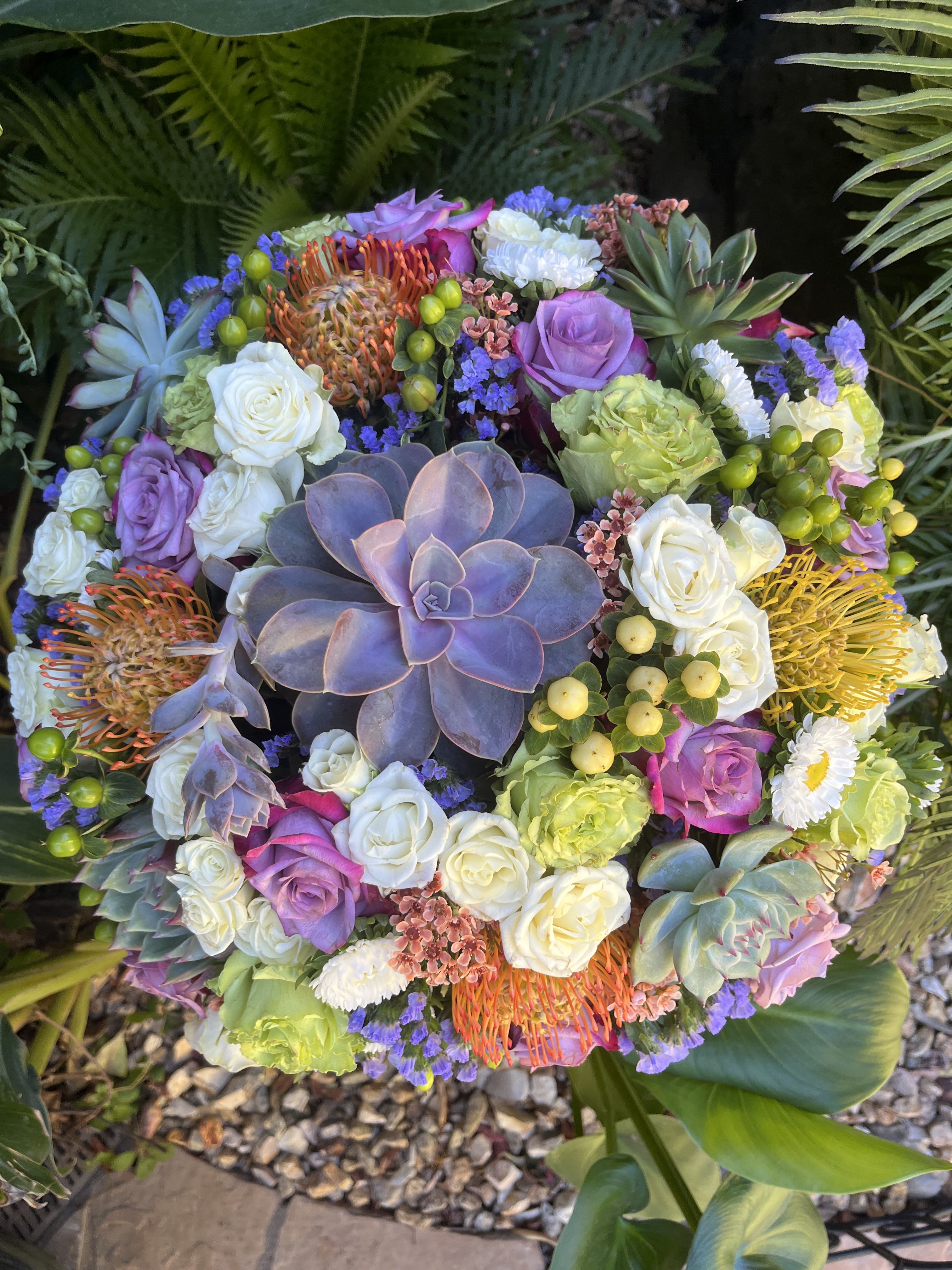 Round bouquet with roses, succulents, and orange pincushion blooms