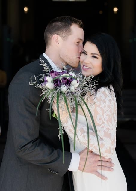 Bride and groom holding a purple and white bouquet