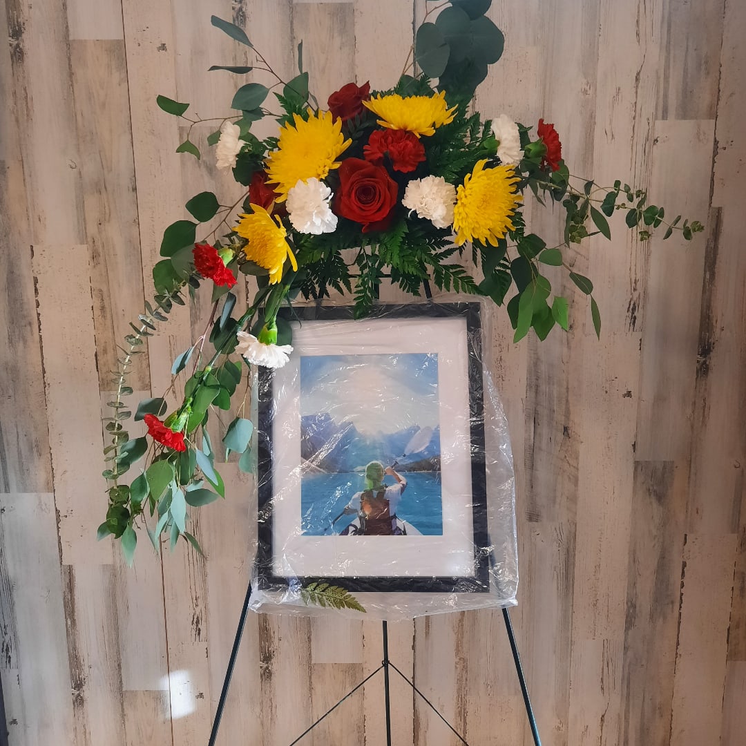 Floral standing spray with red, yellow, and white flowers on an easel