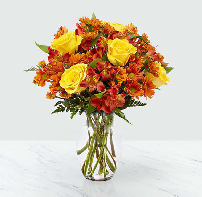 Golden Autumn - This radiant bouquet is beautiful and complex, just like the season itself. Made up of yellow roses, bronze daisy pompons, and red alstroemeria, set in a clear glass vase, the Golden Autumn bouquet truly brings out the best of fall. GOOD bouquet is approx. 14"H x 12"W. BETTER bouquet is approx. 16"H x 13"W. BEST bouquet is approx. 17"H x 15"W. EXQUISITE bouquet is approx. 18"H x 17"W.