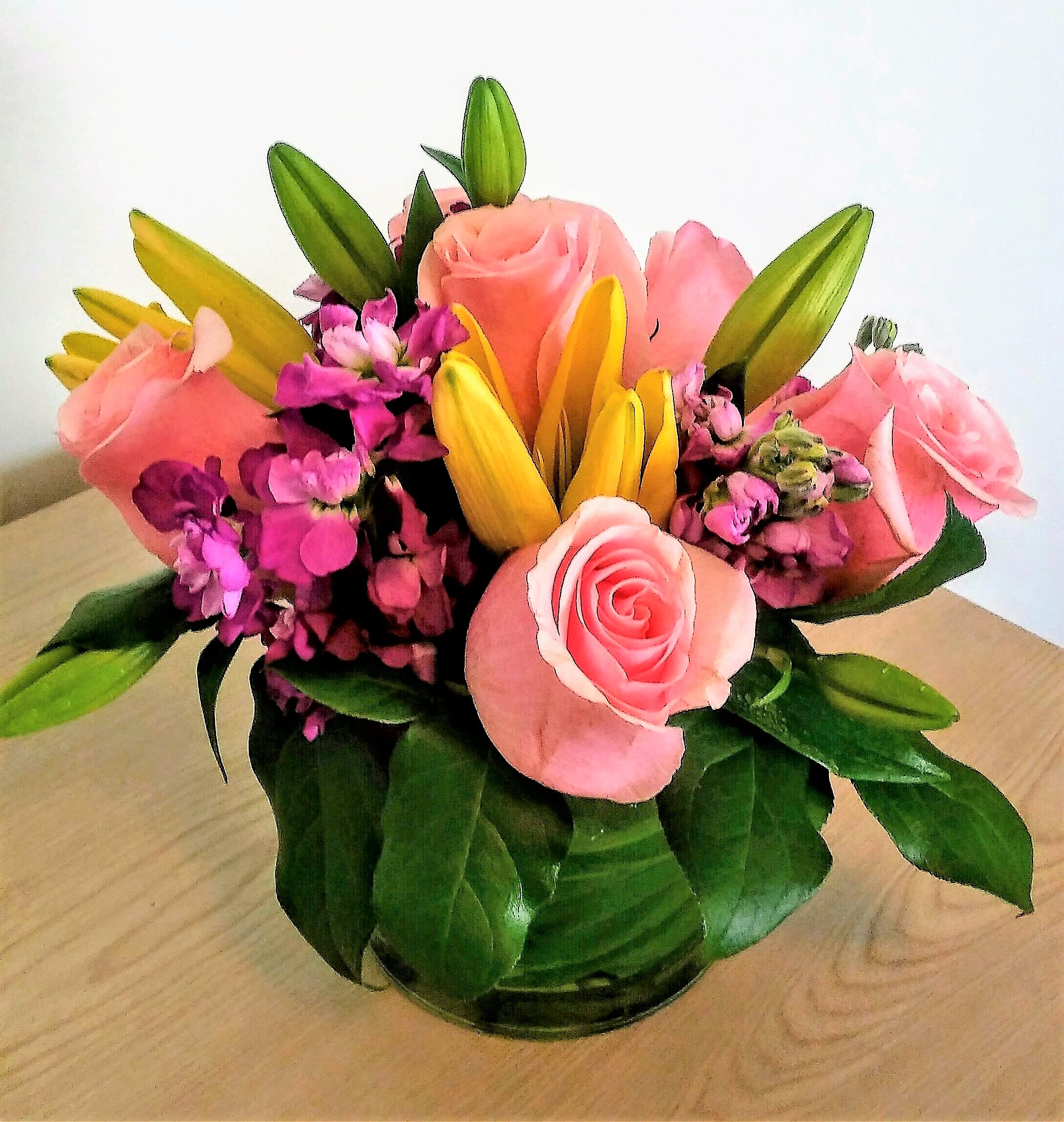 Pink roses and yellow lilies arranged in a glass vase