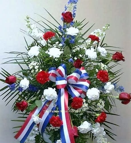 Standing floral spray with red, white, and blue flowers and ribbon
