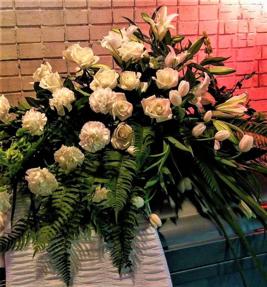 Large white floral arrangement with roses, lilies, and carnations