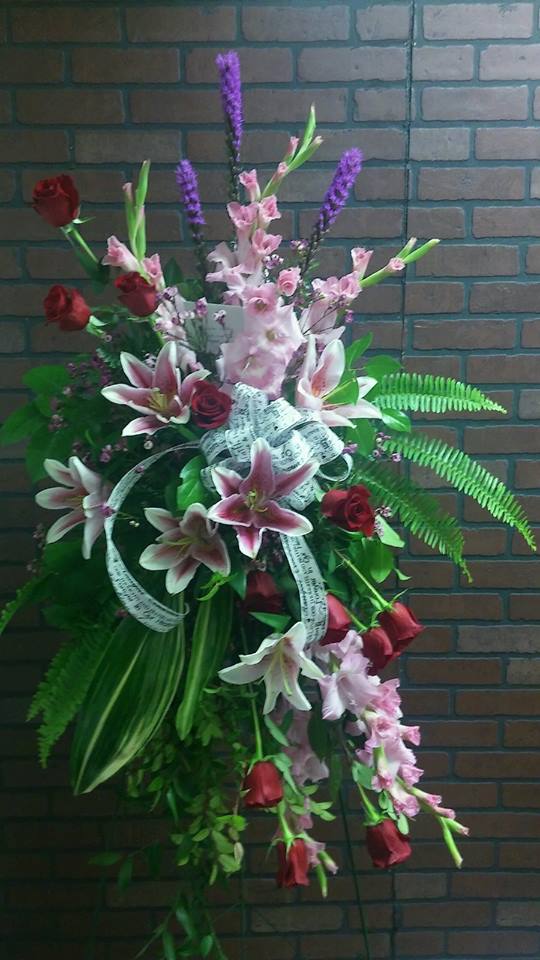 Standing floral spray with pink lilies, red roses, and purple spikes