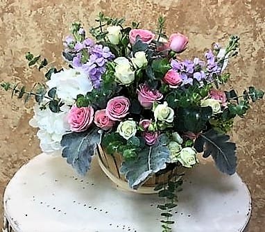 Bouquet of pink and white roses with lavender flowers in a round container