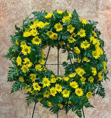 Yellow daisy wreath on a black stand