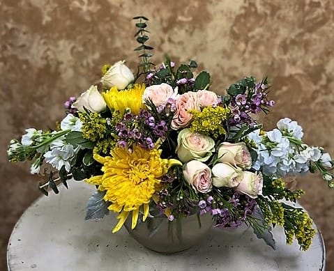 Mixed bouquet of roses, yellow chrysanthemums, and small purple flowers in a vase