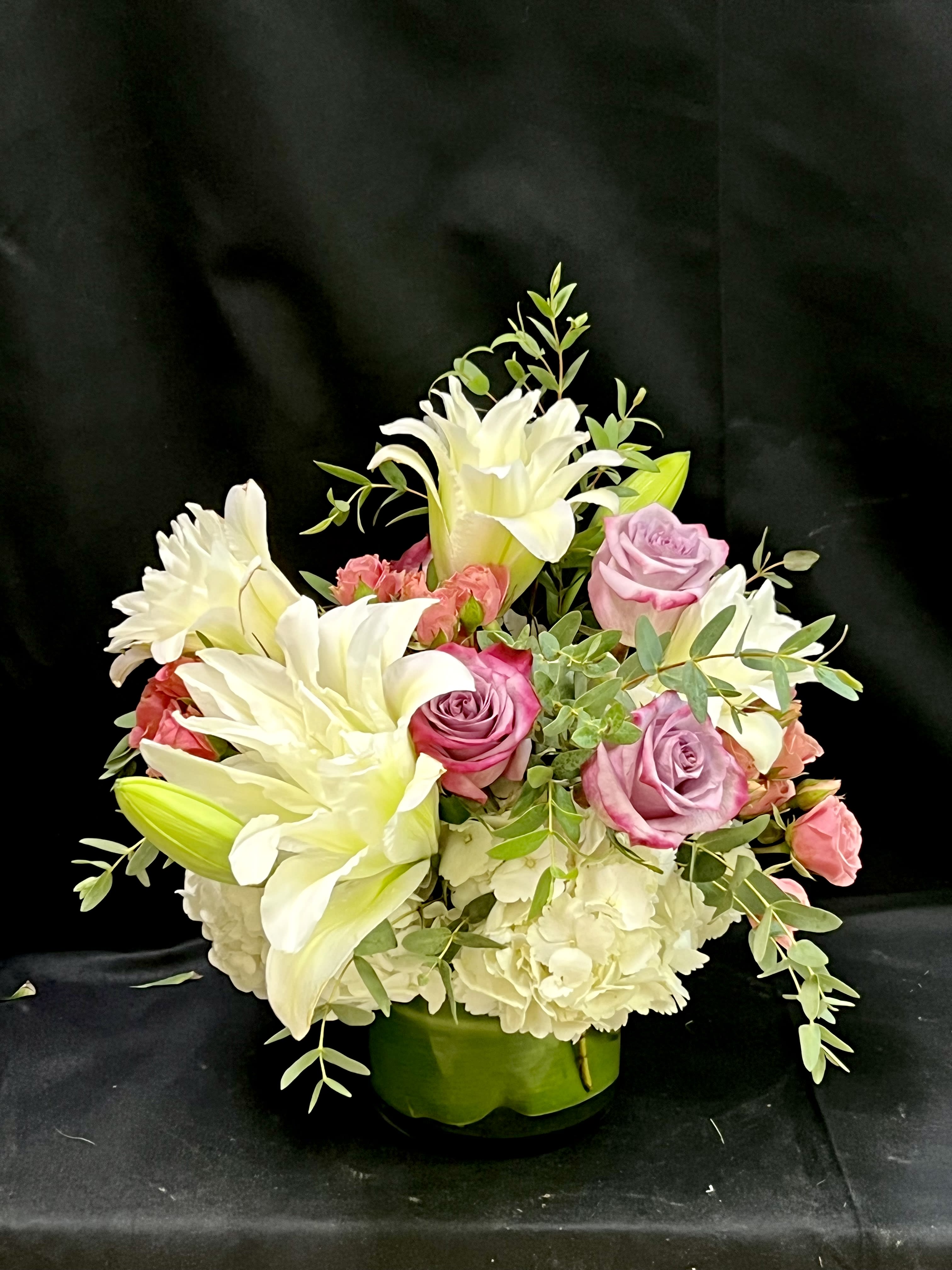 Pink roses and white lilies arranged in a green vase