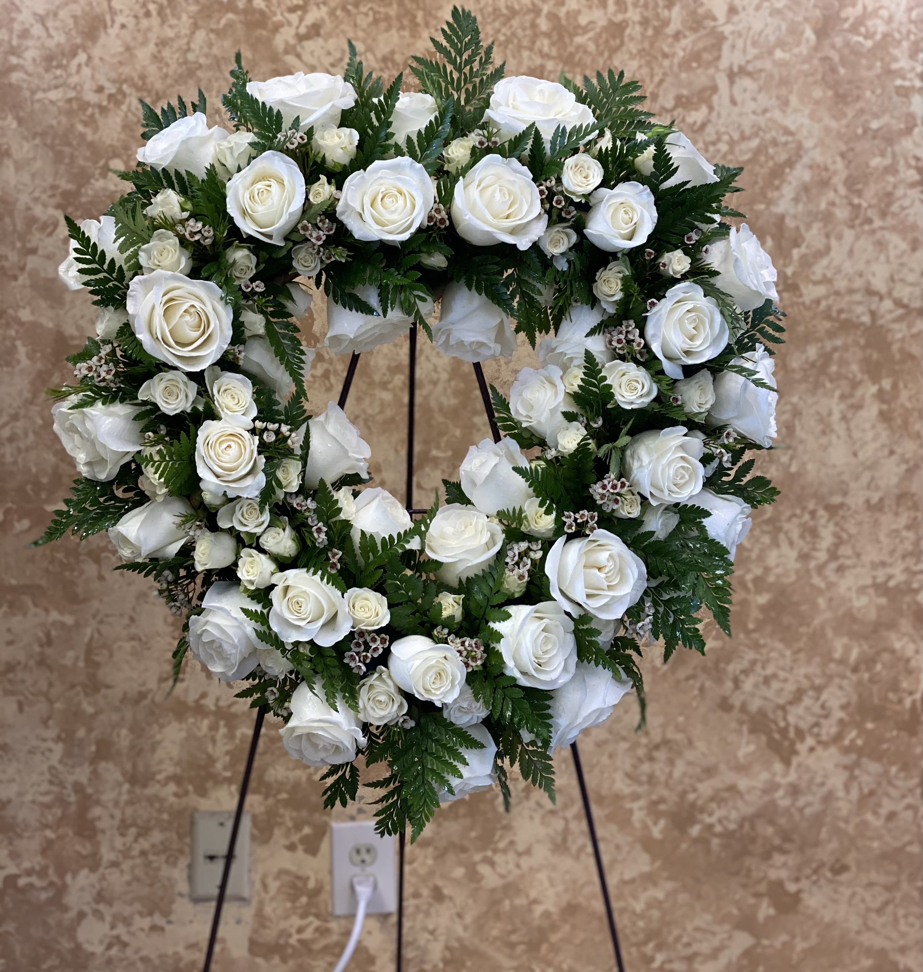 Heart-shaped wreath of white roses on a stand