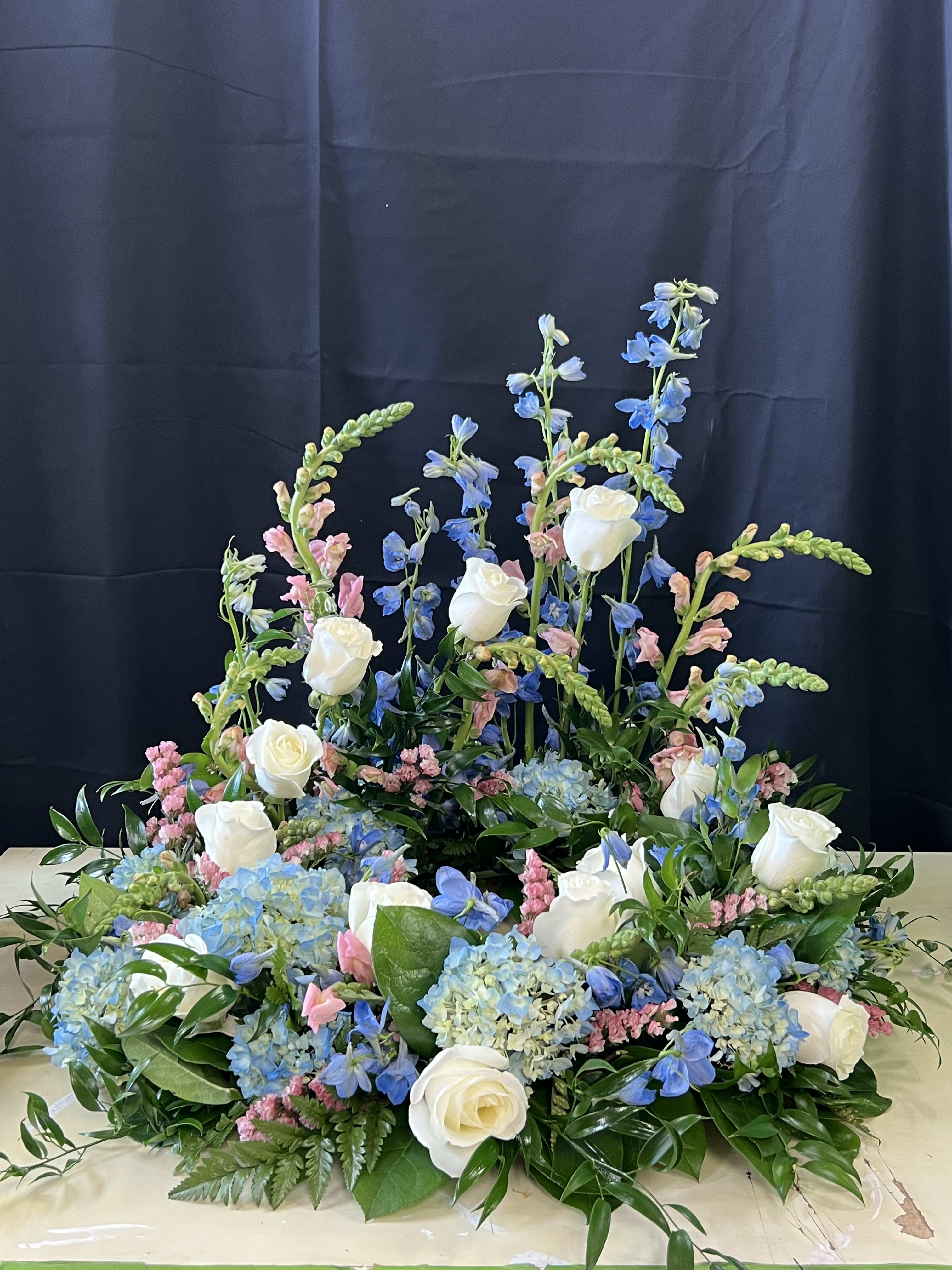 Large floral arrangement with white roses, blue blooms, and pink accents