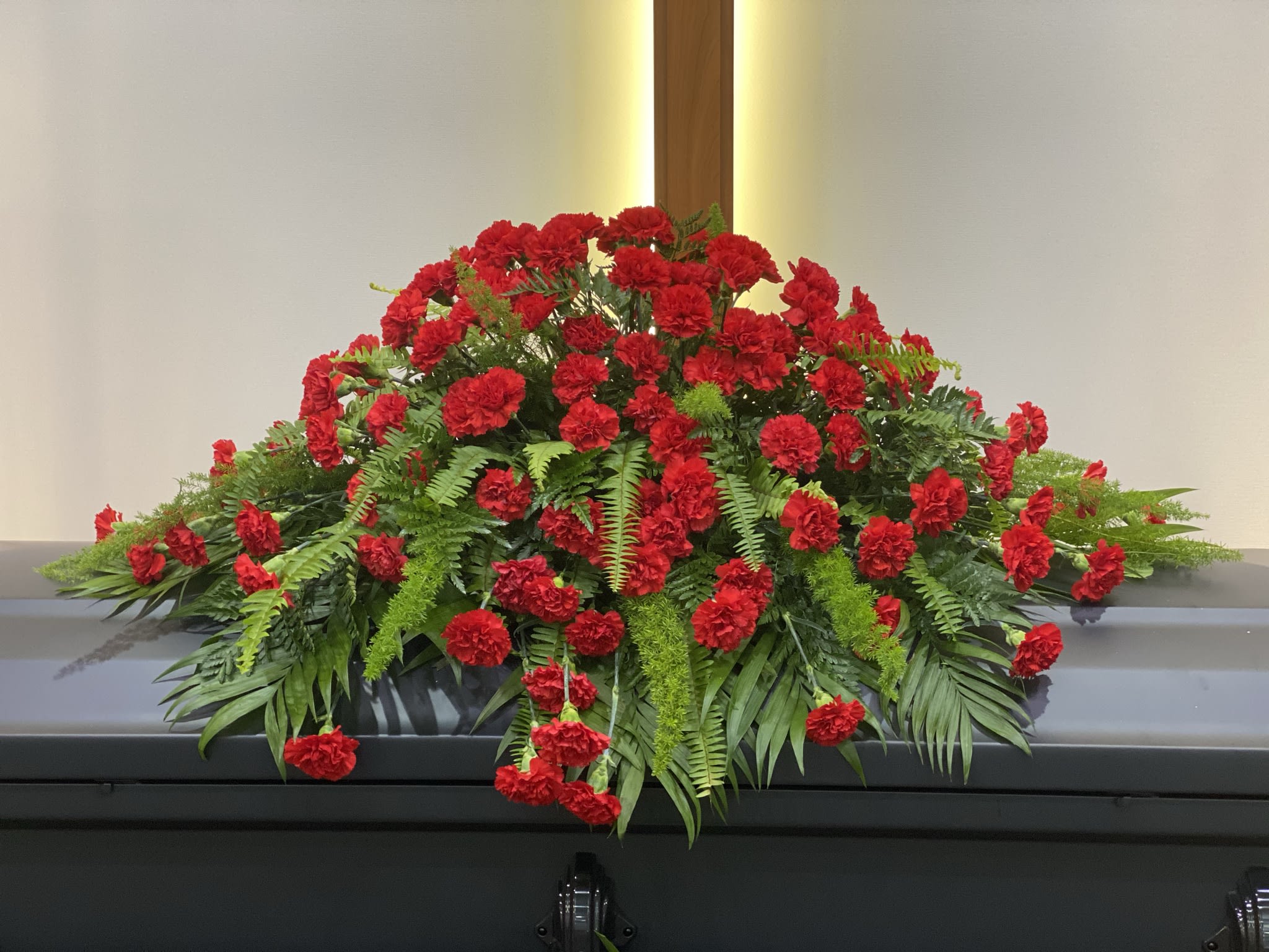 Red carnation casket spray - Deluxe shown- casket spray of robust, red carnations makes an impressive display for that someone special.