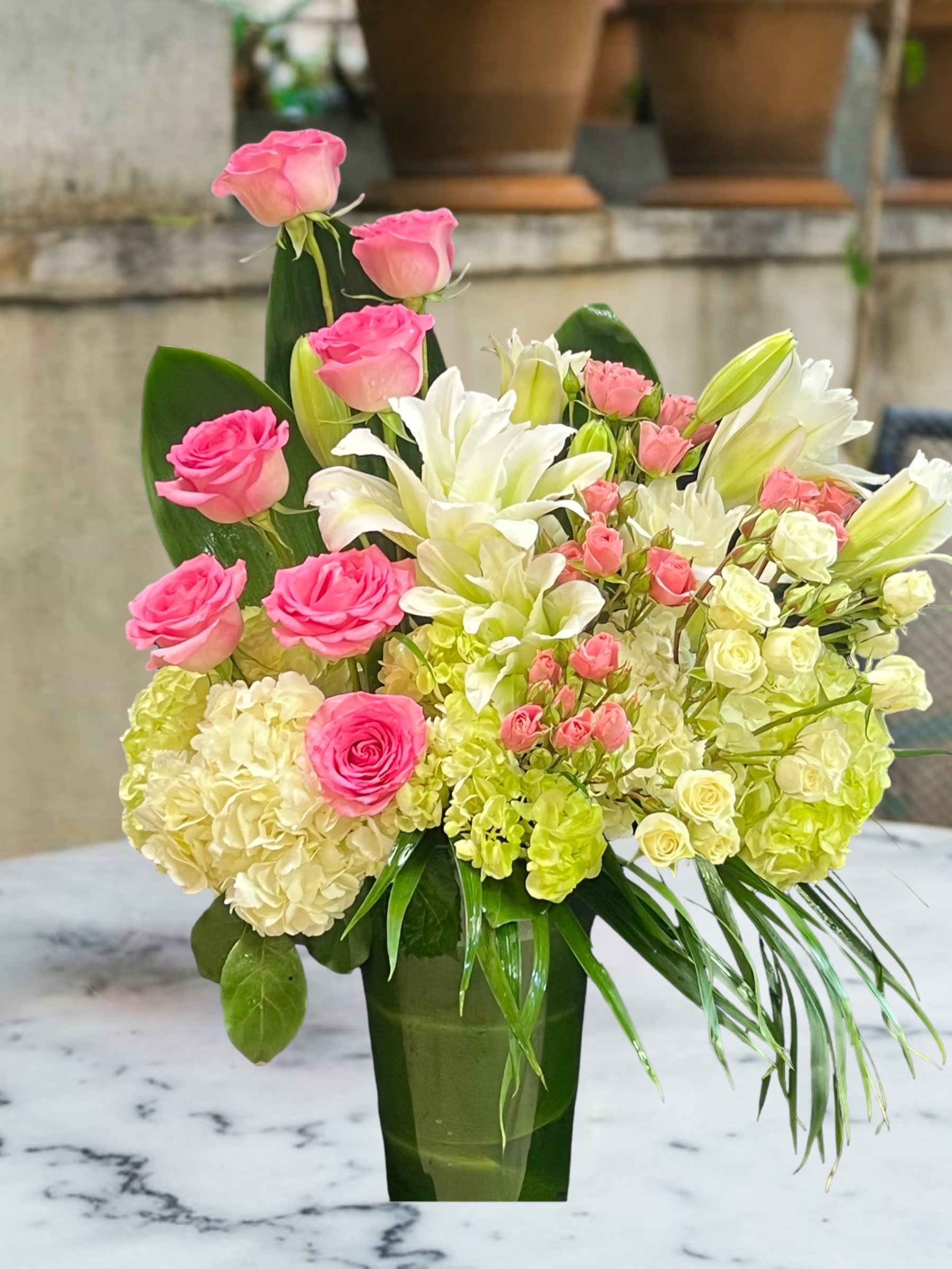 Pink roses and white lilies arranged in a tall green vase