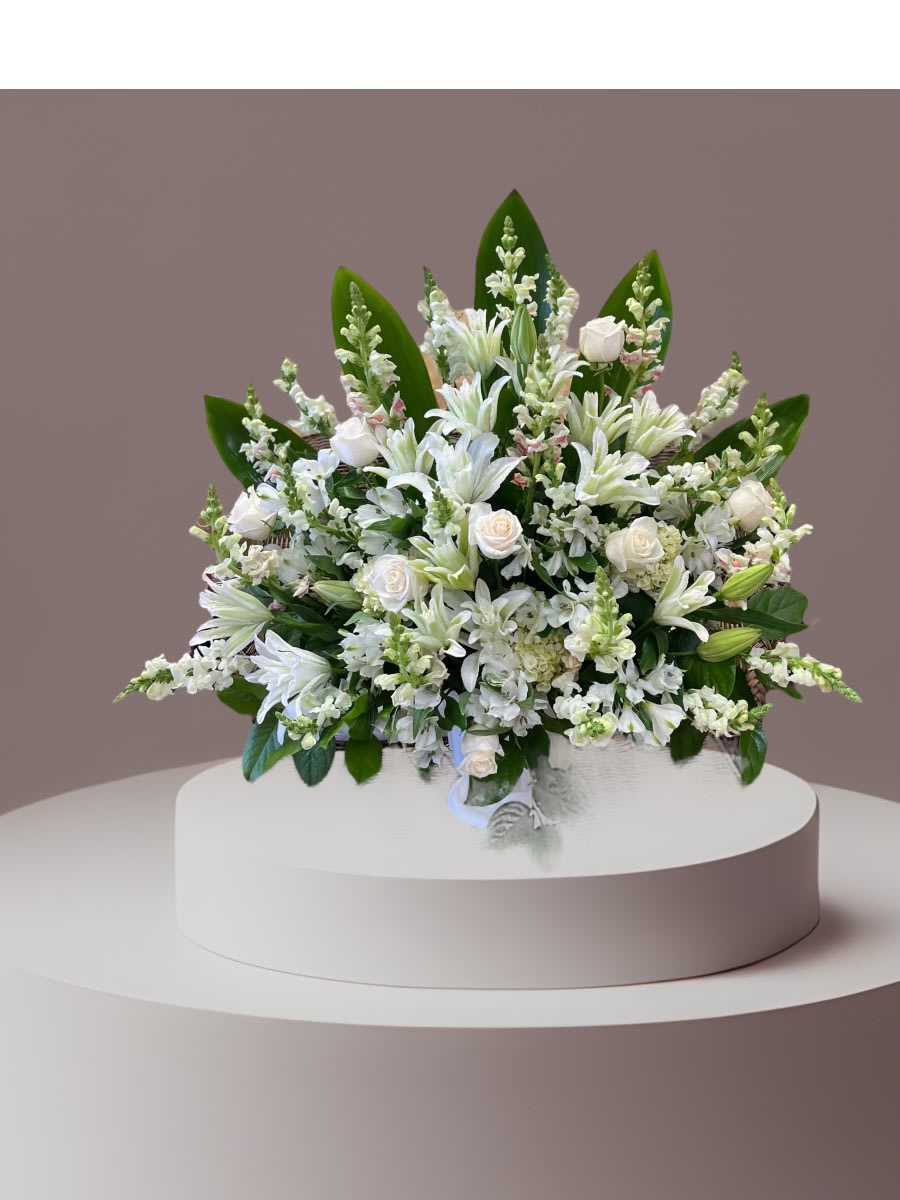 White floral arrangement in a low basket on a pedestal