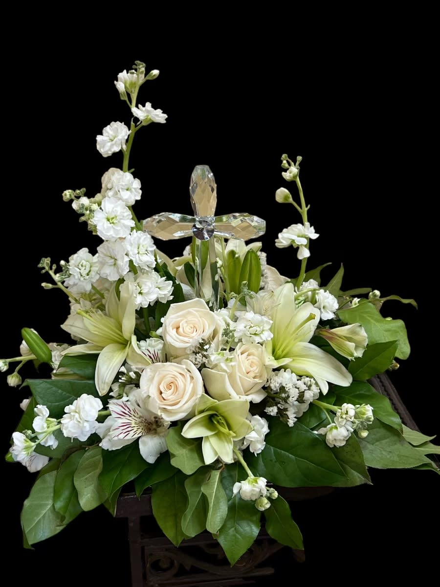 White floral arrangement with roses, lilies, and a crystal cross