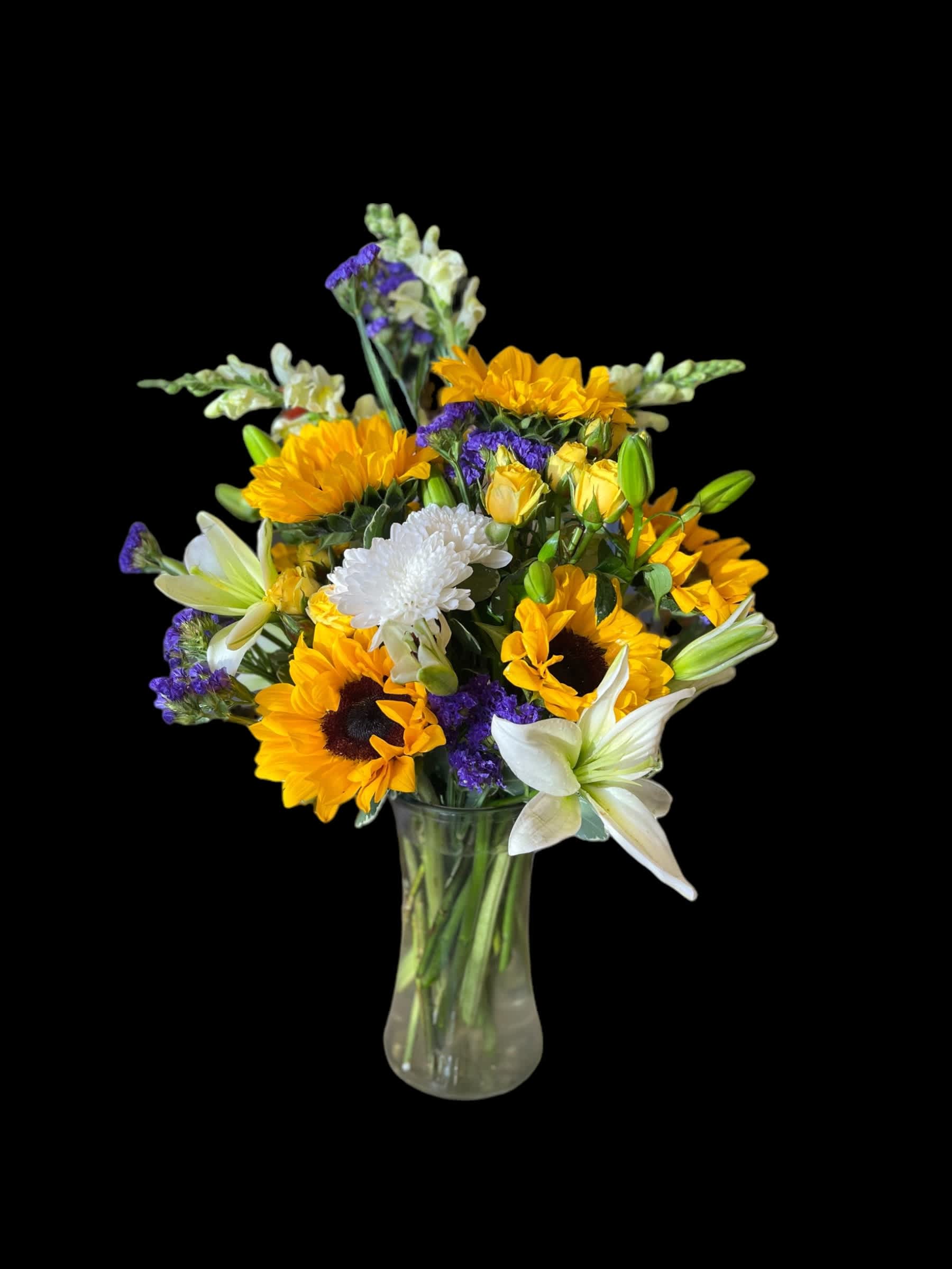 Bouquet of sunflowers, white lilies, and purple filler in a glass vase