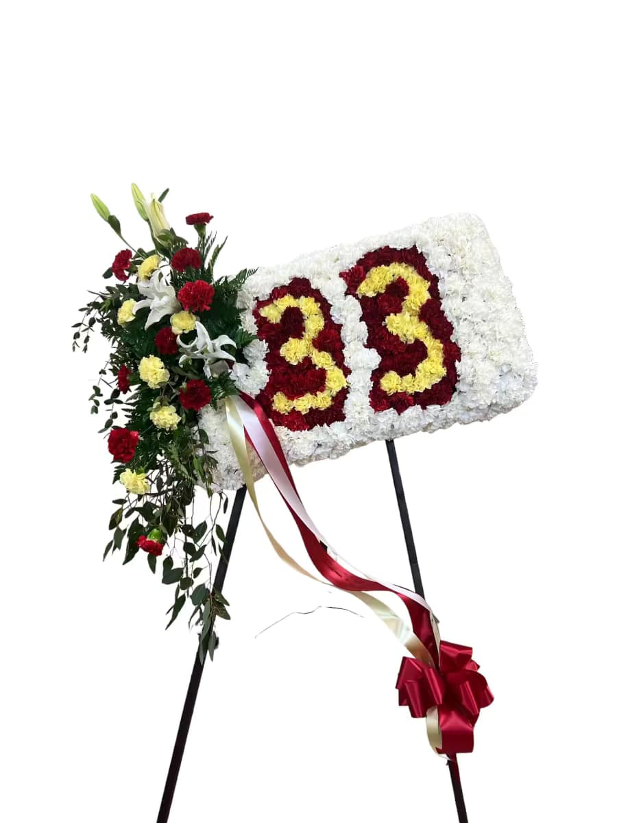 Floral standing tribute with white, red, and yellow flowers on an easel