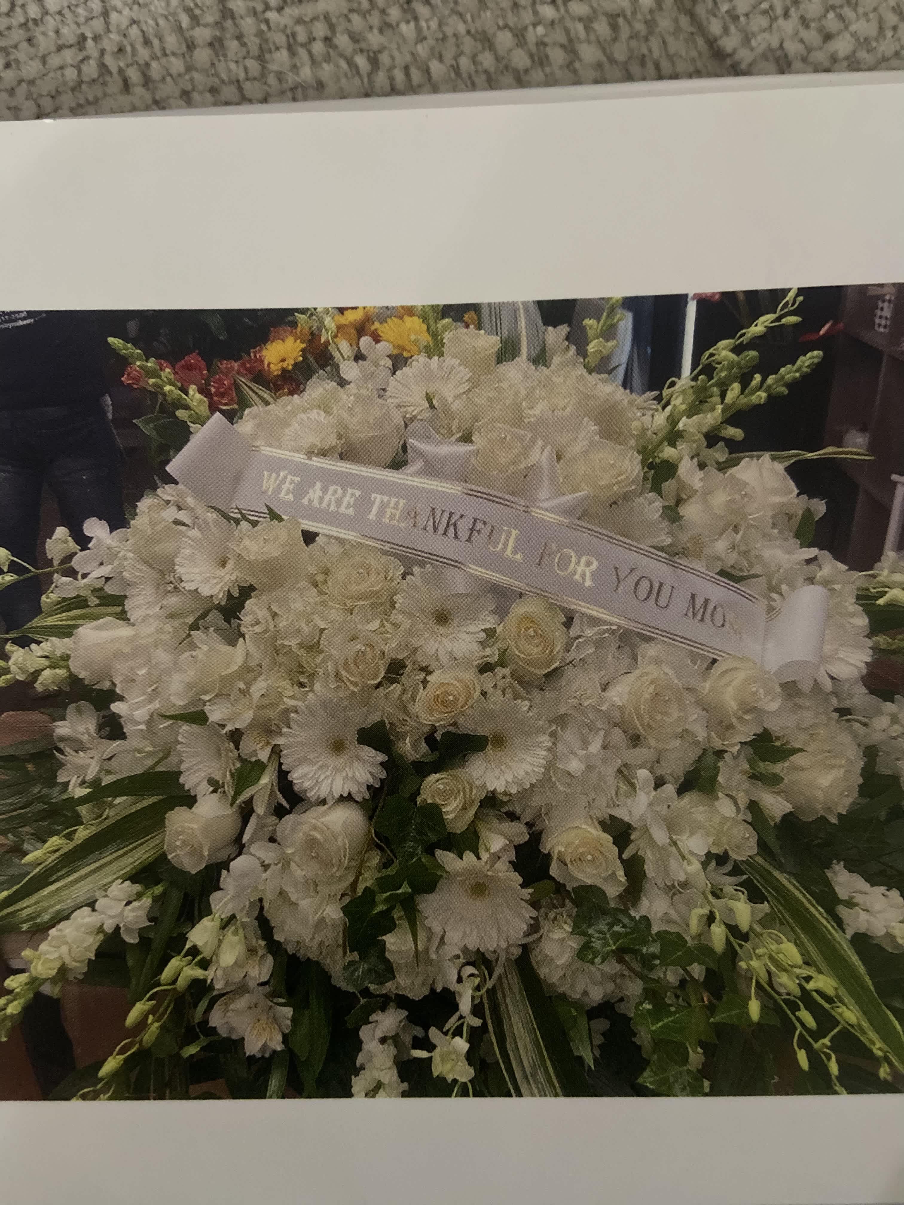 Large white sympathy floral spray with a thank-you ribbon
