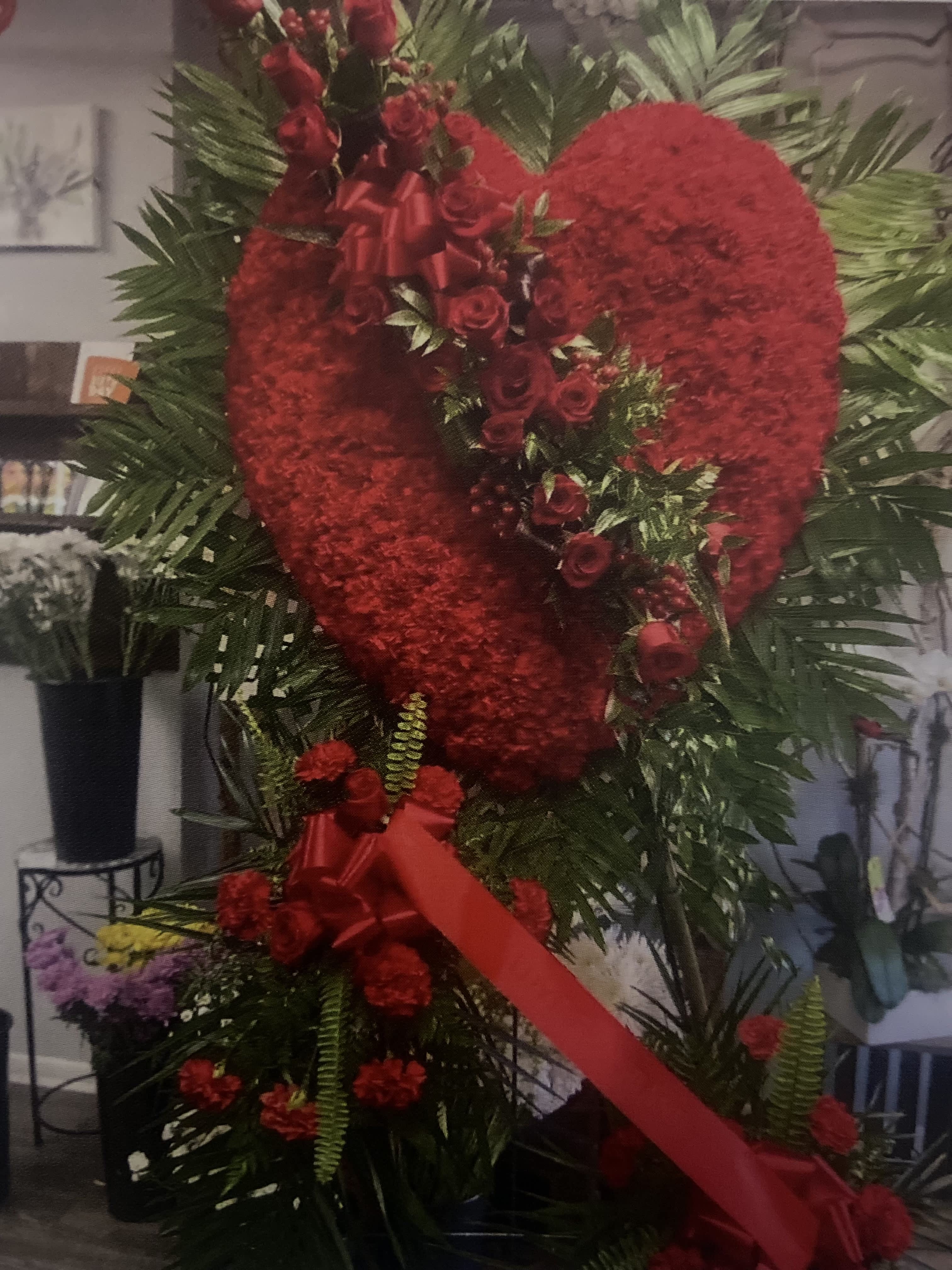 Heart-shaped red floral standing tribute with roses and ribbon