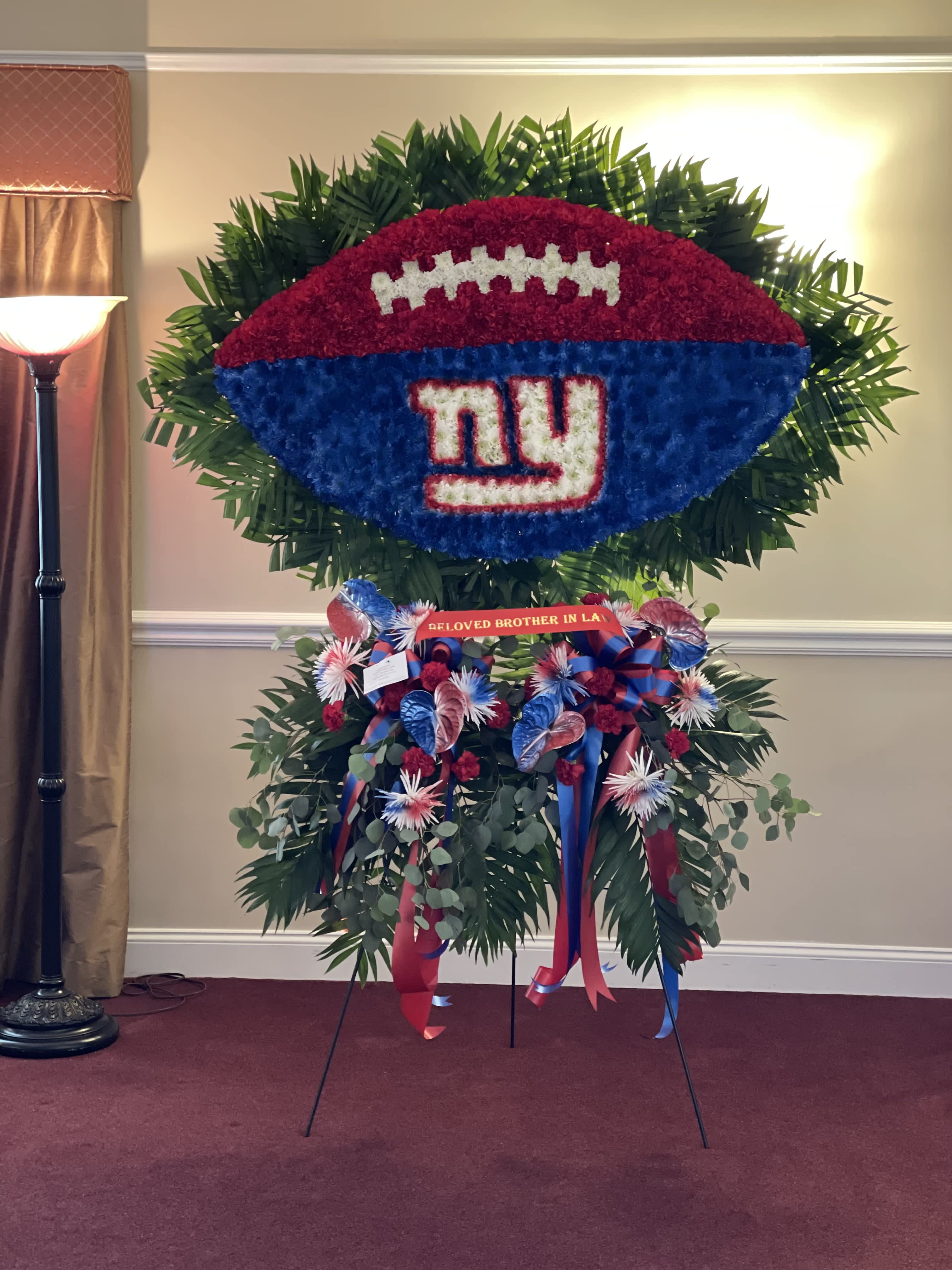 Large football-shaped floral tribute with a Giants logo and ribbon accents