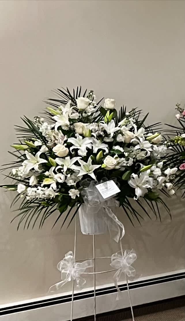 White lilies and roses in a standing spray with a ribboned easel
