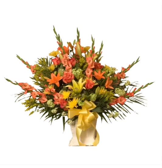 Orange and yellow mixed flower arrangement in a vase with a gold ribbon