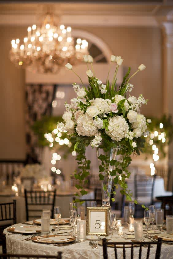 Tall white floral centerpiece in a clear vase on a banquet table