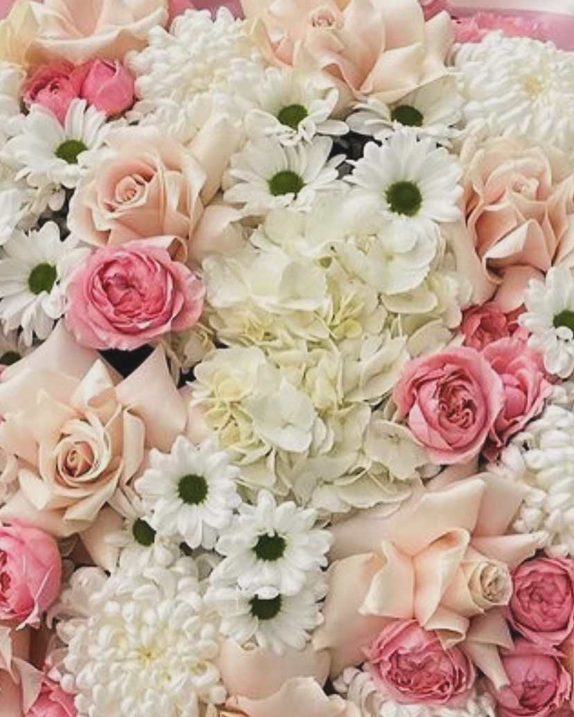 Pink and cream roses with white daisies and hydrangeas in a dense bouquet.