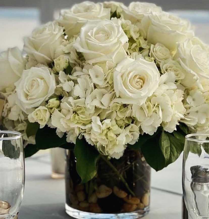 White roses and hydrangeas arranged in a glass vase