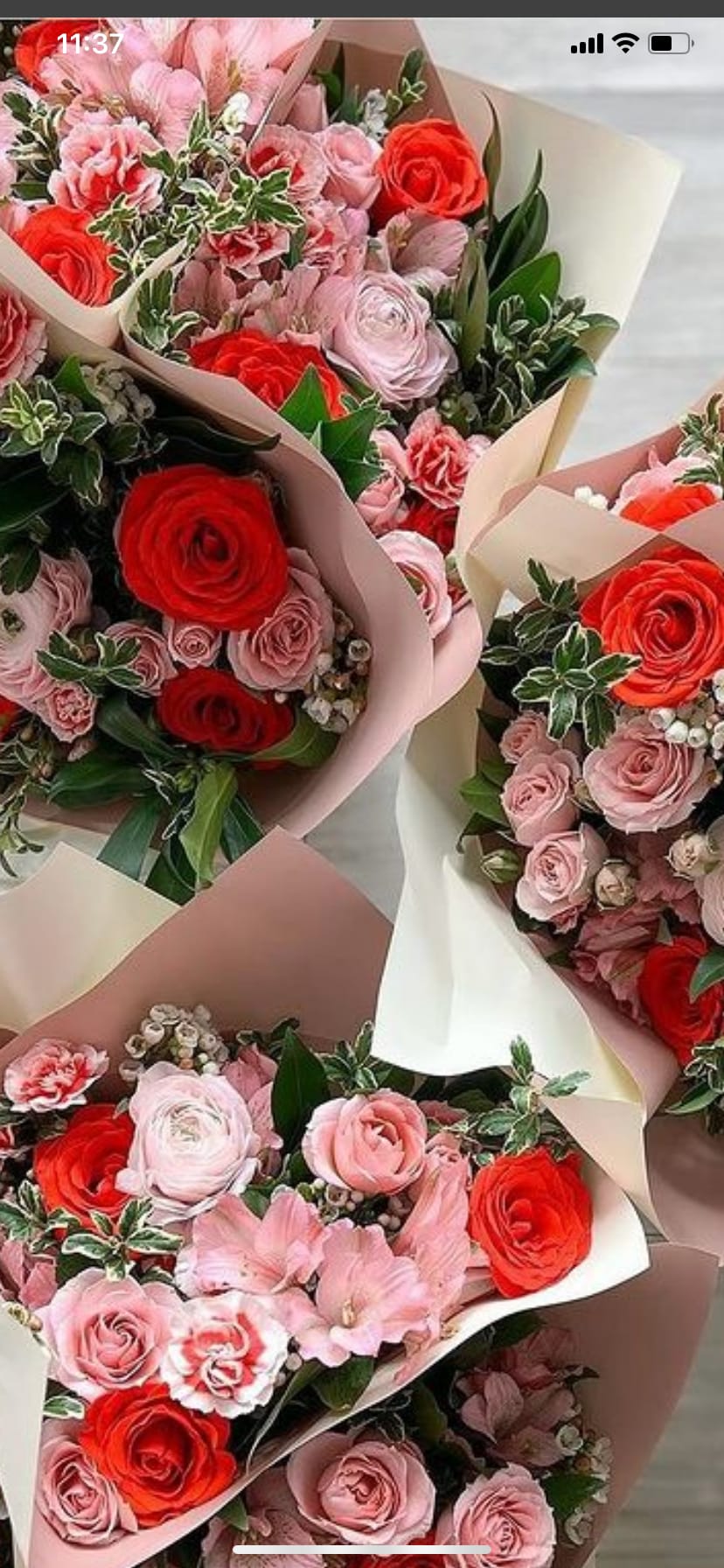 Several bouquets of pink and red roses wrapped in pastel paper