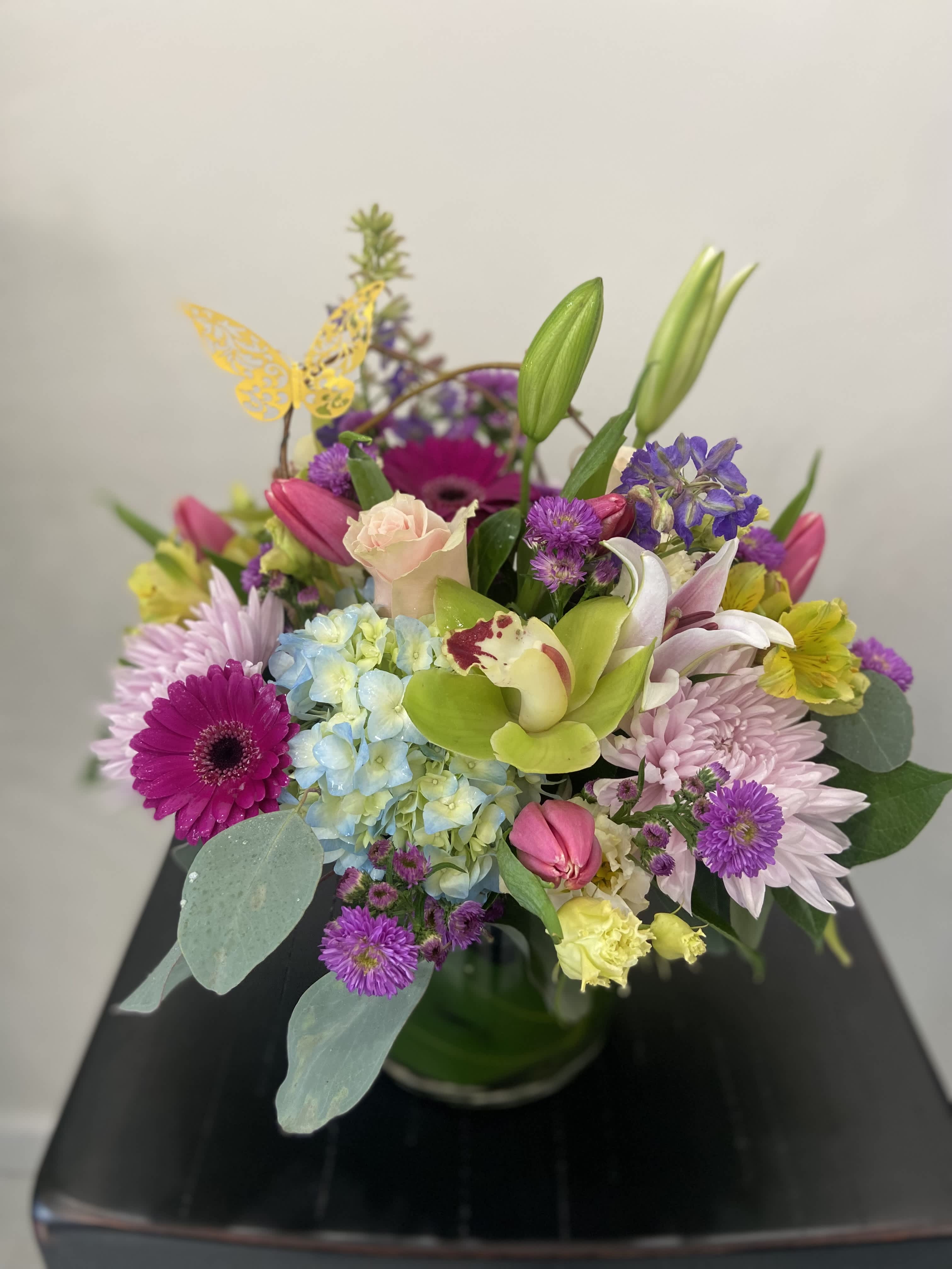 Colorful mixed bouquet in a glass vase with lilies, roses, and daisies