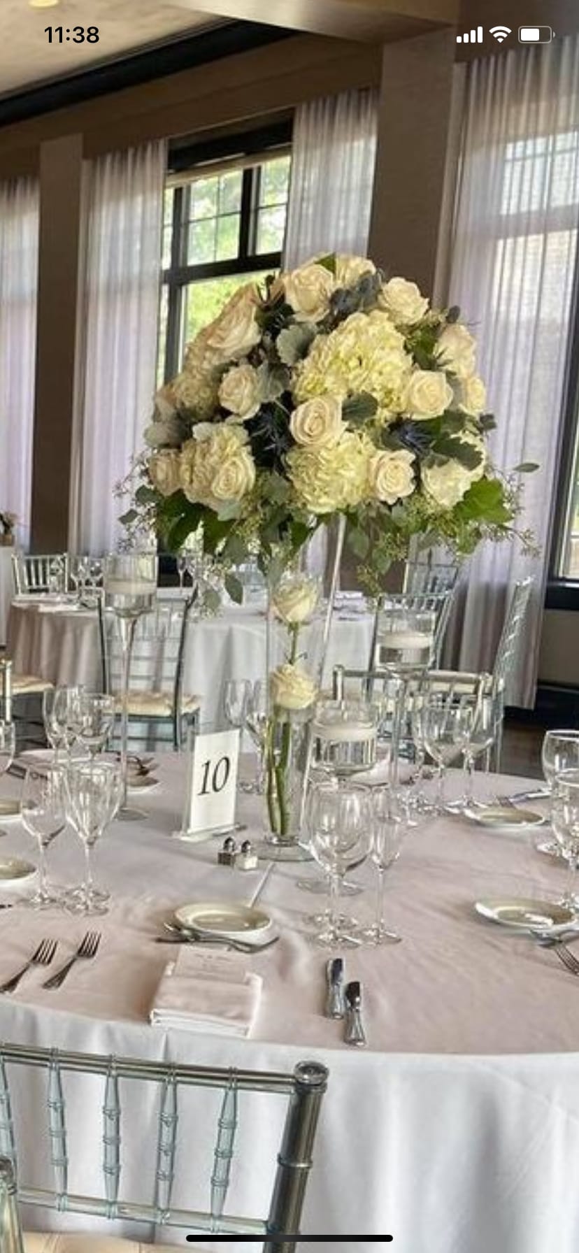 Tall cream rose centerpiece in a clear glass vase on a banquet table