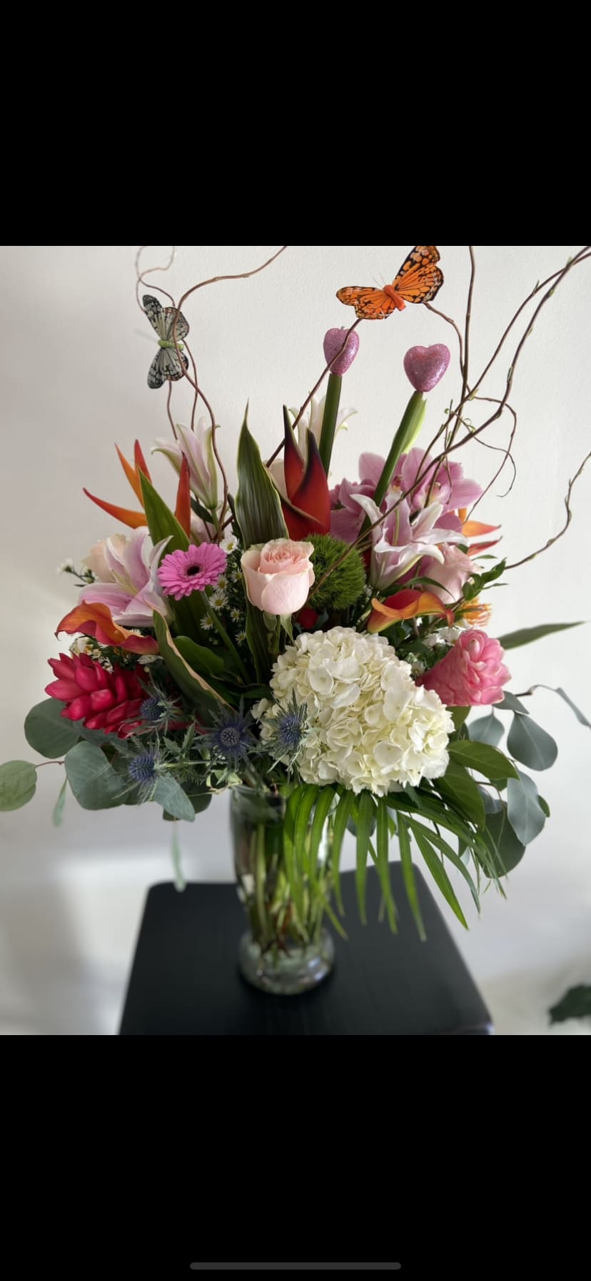 Mixed tropical bouquet in a glass vase with butterfly picks