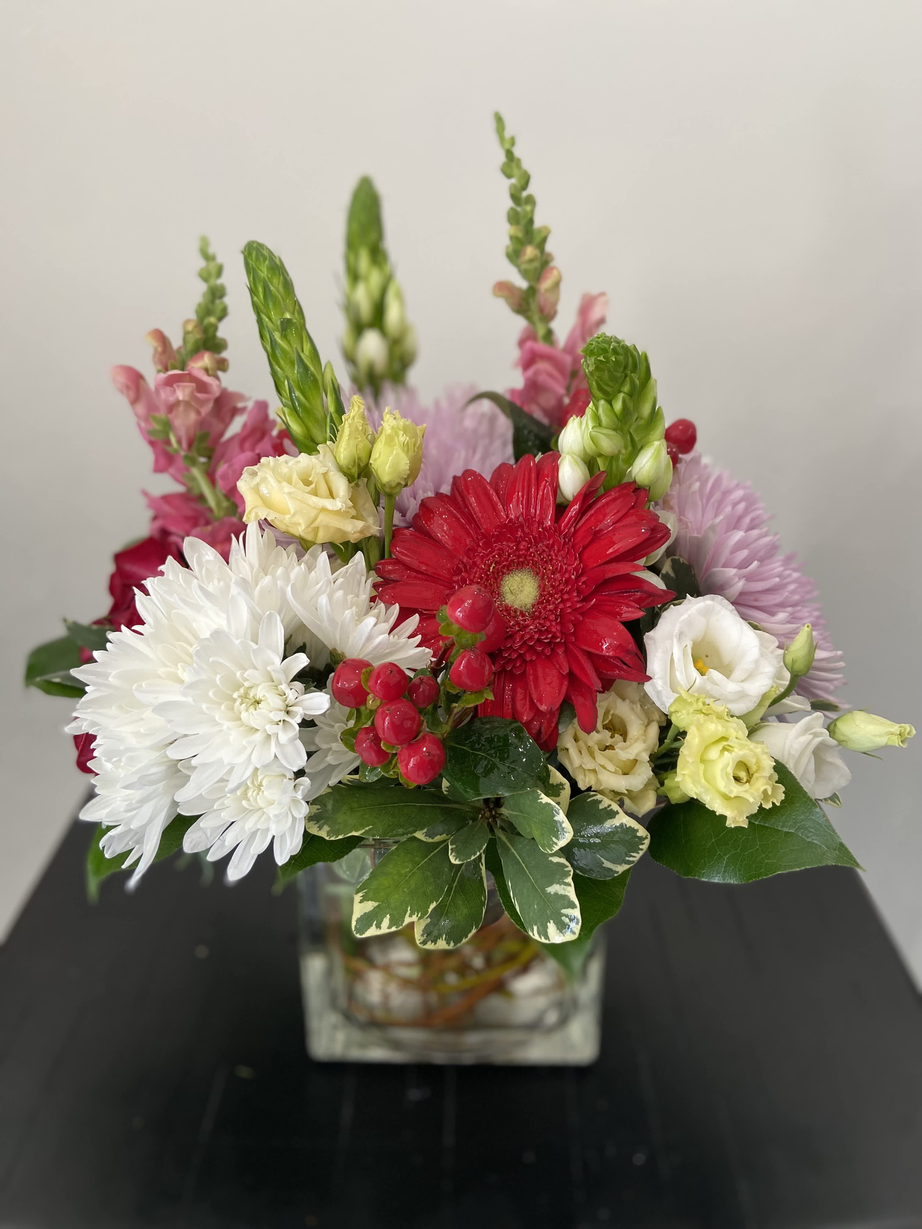 Mixed bouquet in a square glass vase with red, white, pink, and yellow blooms