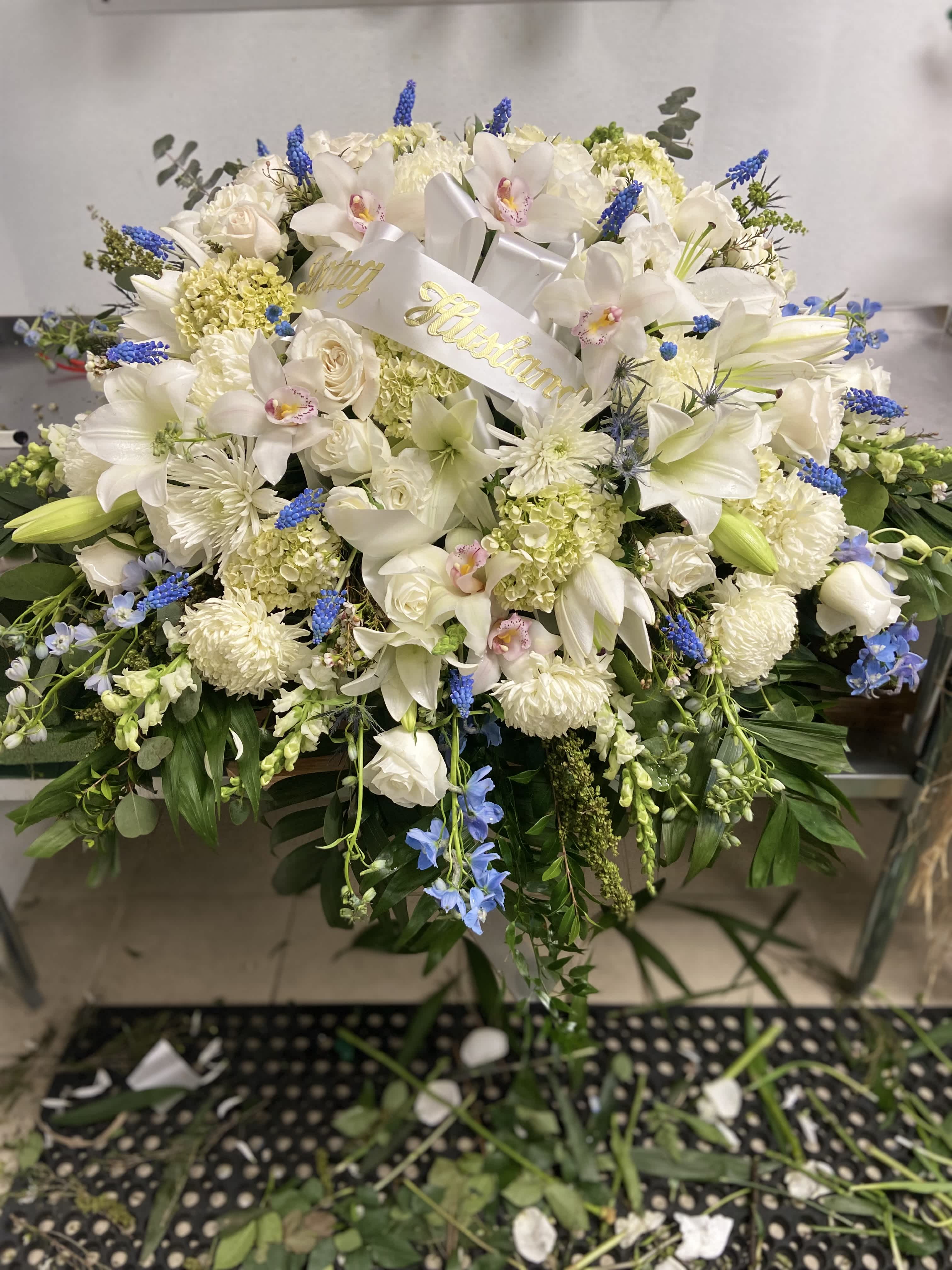 White floral spray with lilies, orchids, and blue accents