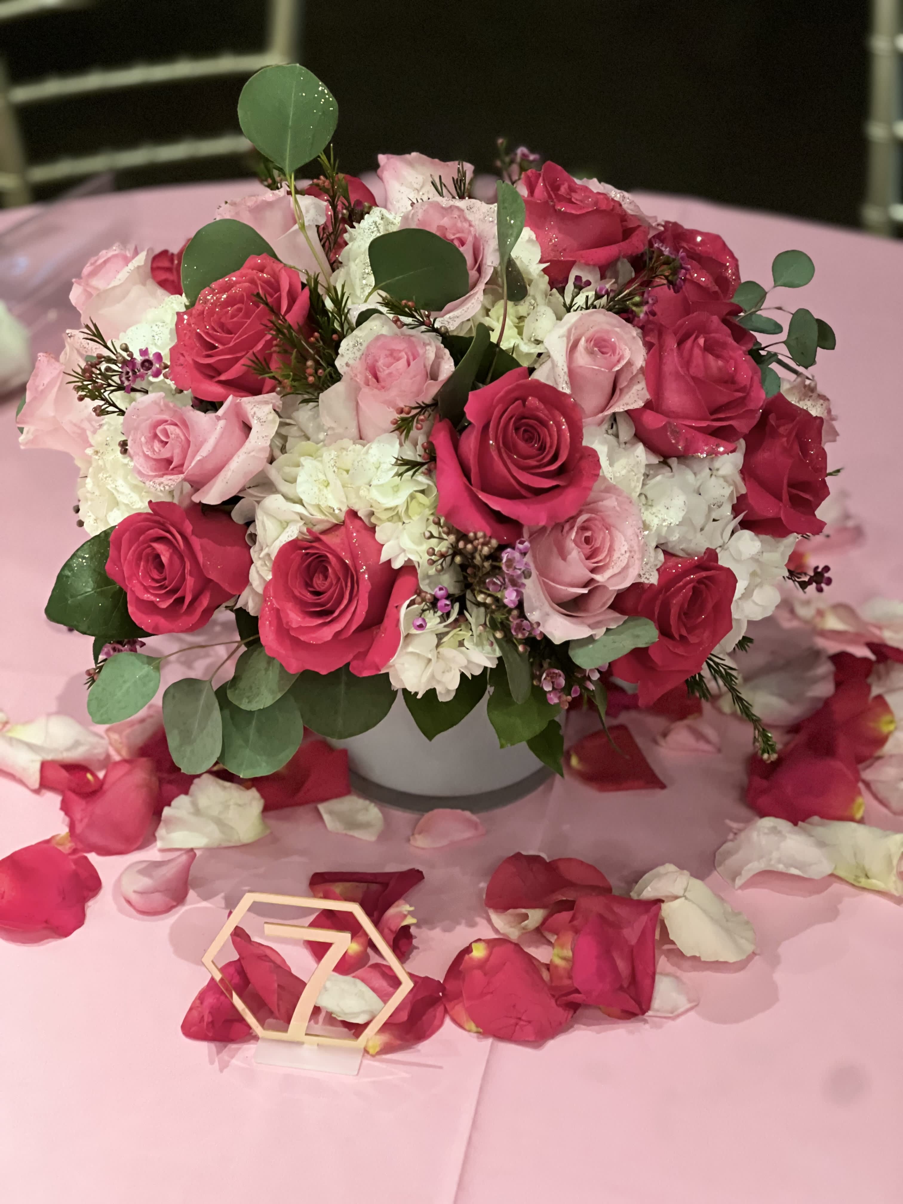 Pink and white rose arrangement in a white vase on a pink table