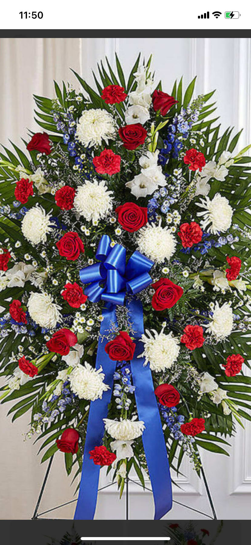 Standing floral spray with red roses, white blooms, and blue ribbon