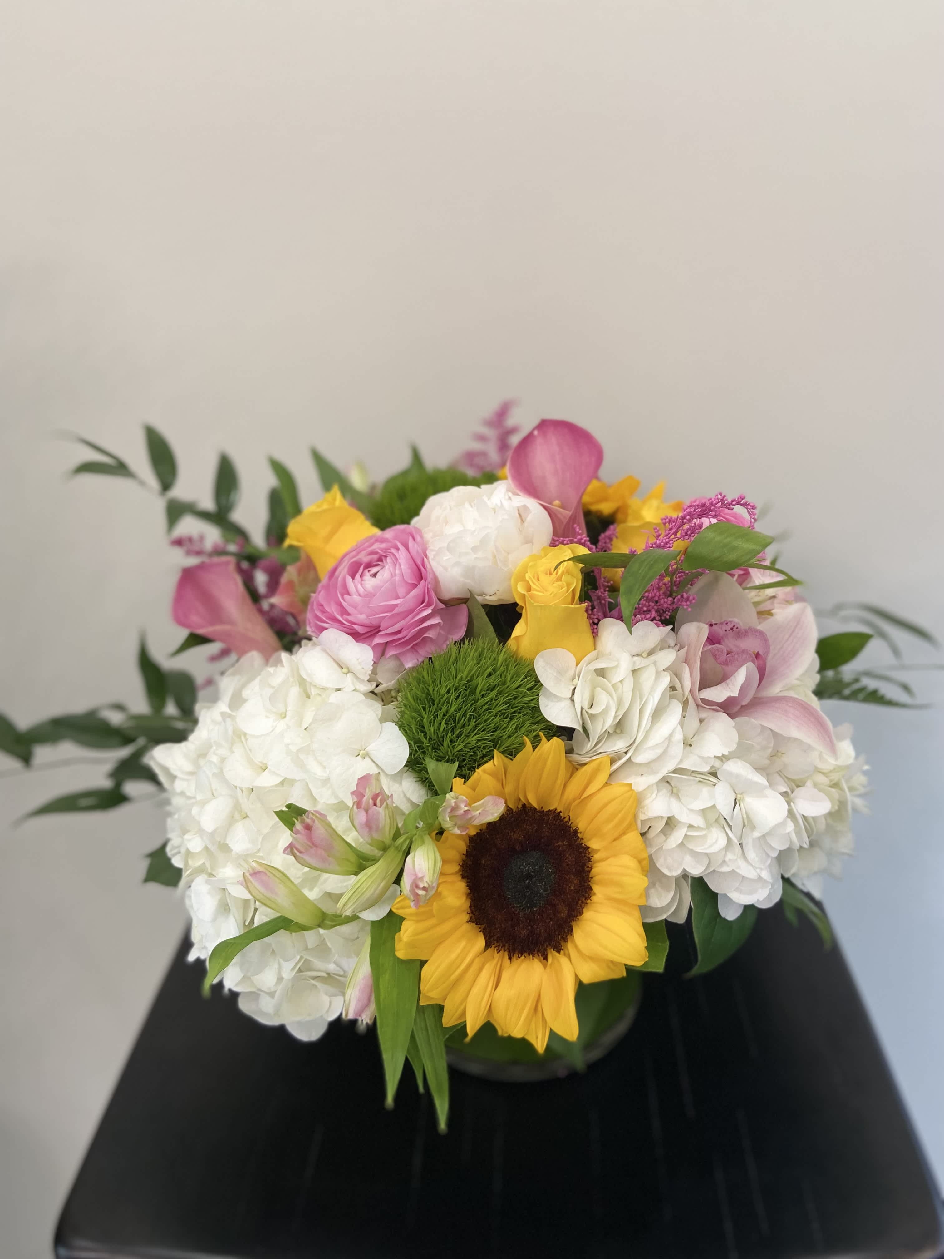 Mixed bouquet with a sunflower, white hydrangeas, and pink roses in a vase
